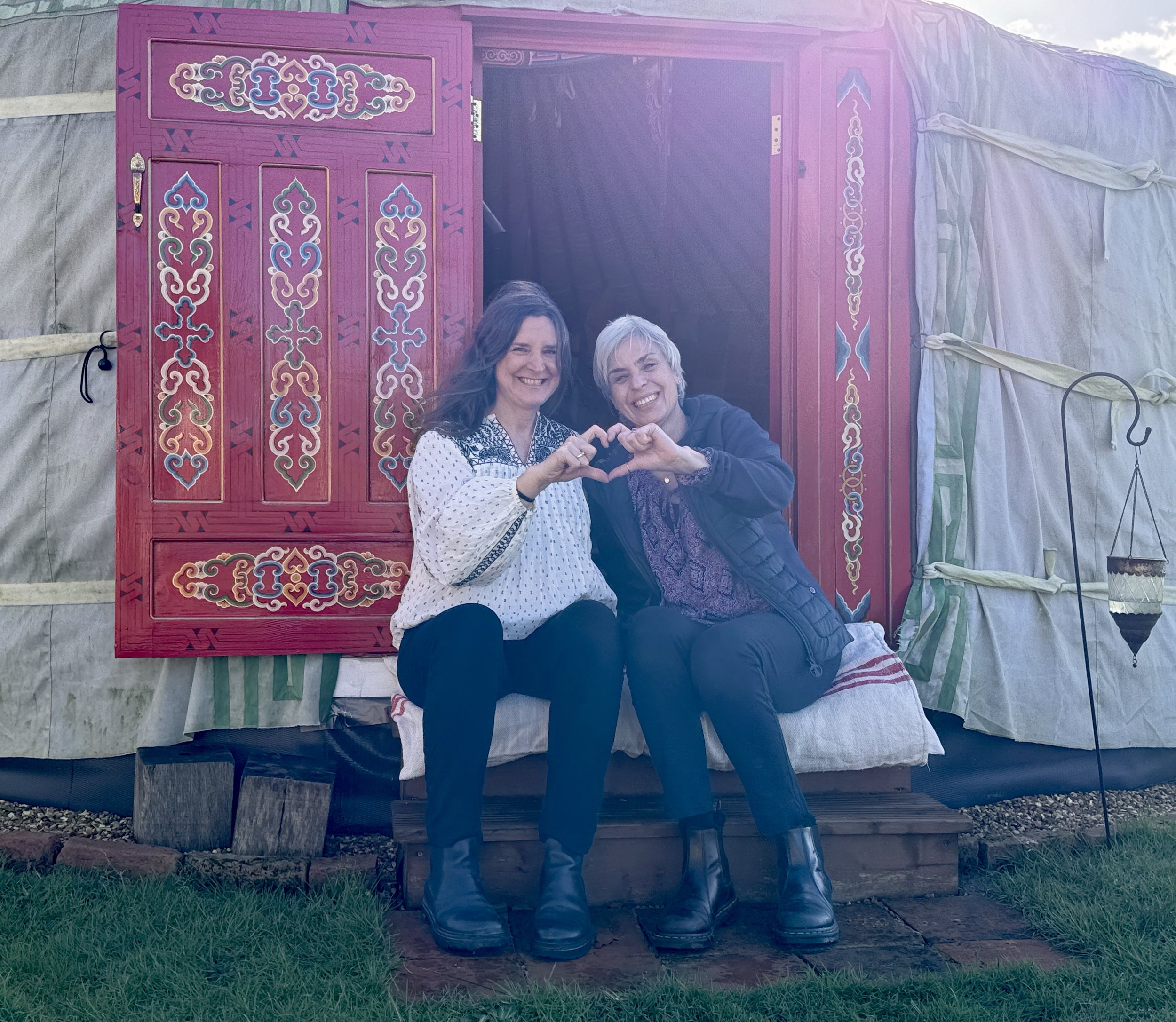 Bex and Debbie outside yurt - heart hands.jpg