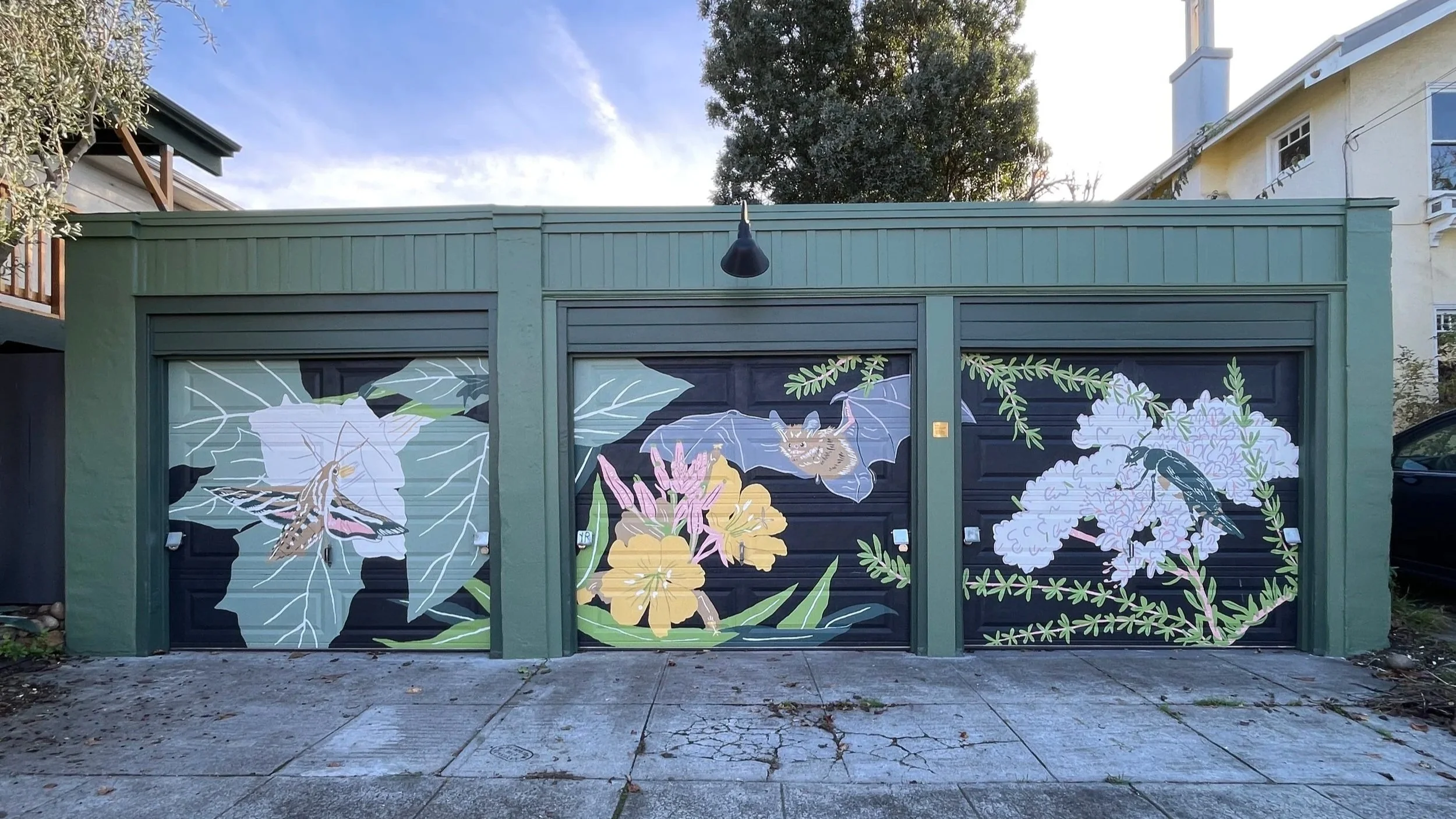 A mural on three garages featuring night pollinators - a month, a bat, and a beetle on California native plants