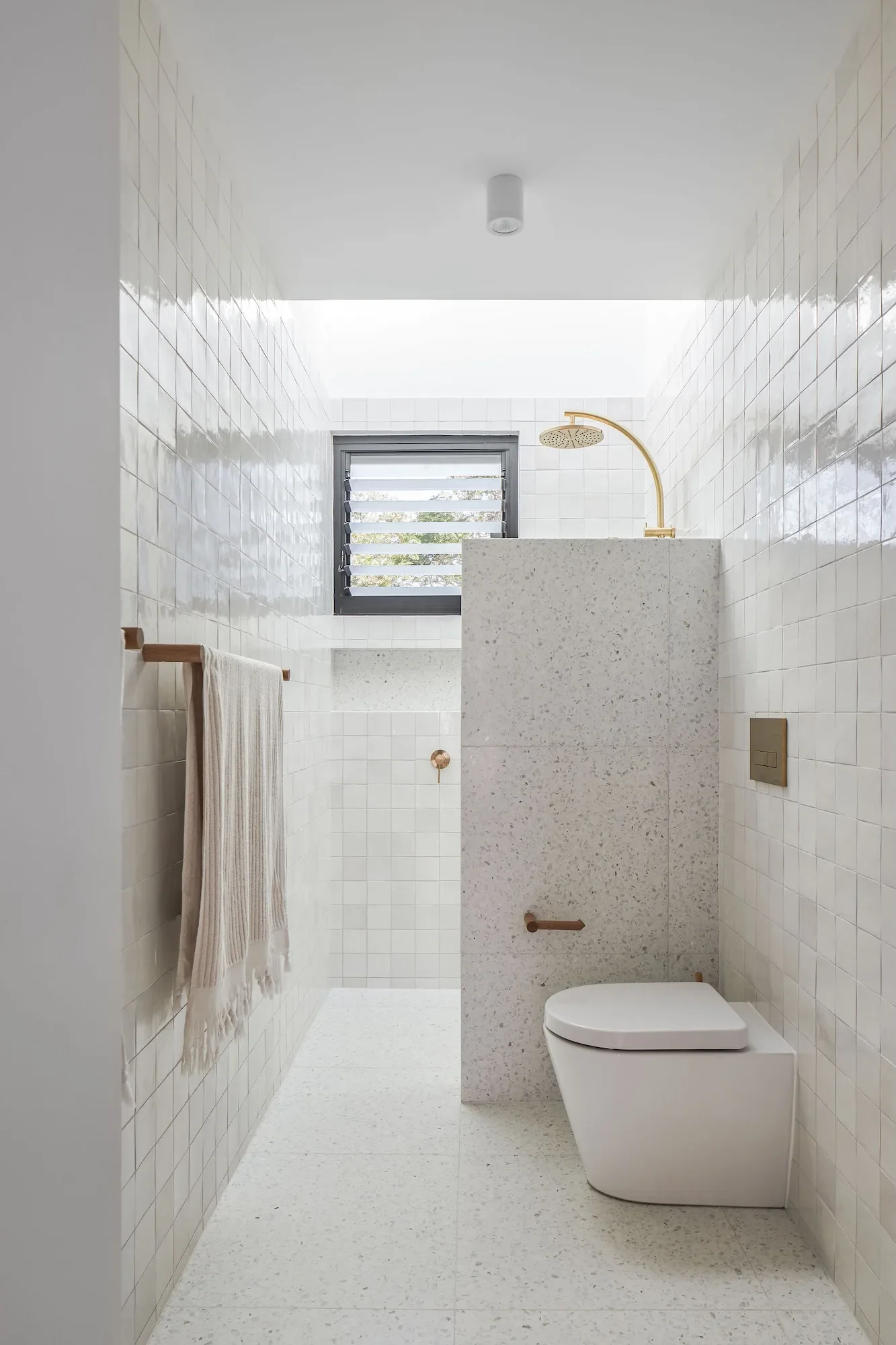 Compact bathroom with terrazzo finishes and skylight bringing in natural light.