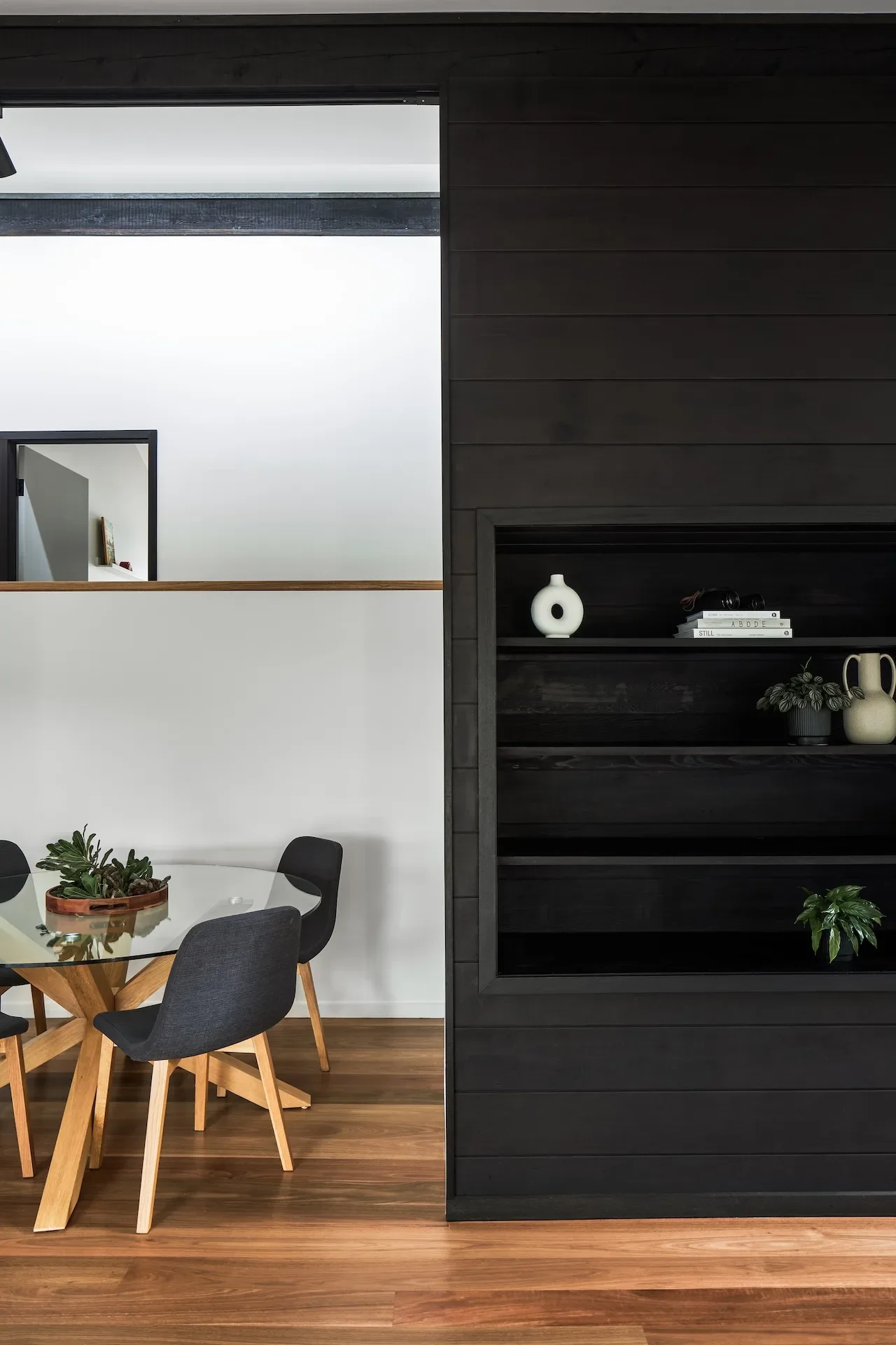 Dining nook with custom shelving and dark joinery, balancing warmth and functionality.