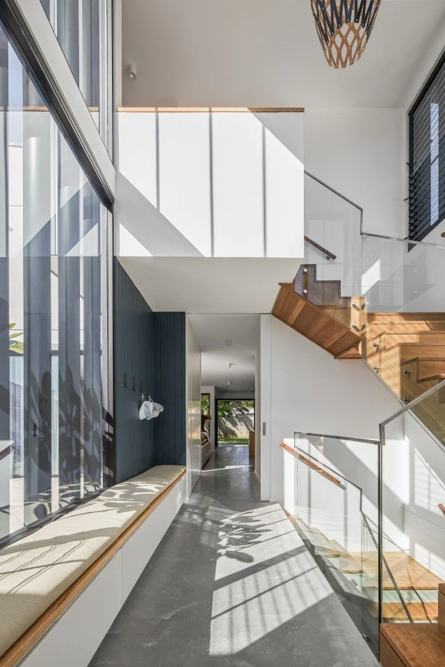 light filled hallway in house full of light with floor to ceiling windows, a long window seat, and an open staircase leading to the upstairs rooms