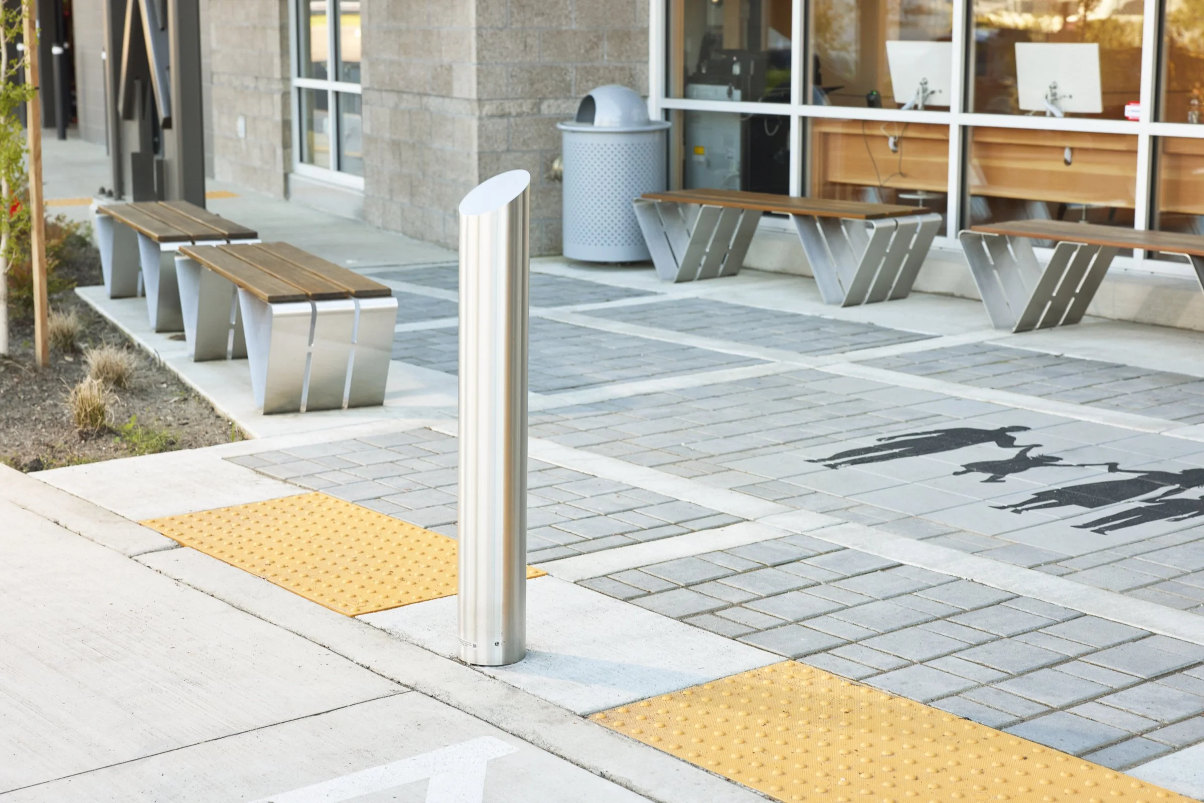 Outdoor space showing tactile paving and a stainless steel bollard at a modern office space in Canby, Washington. Huntco Douglas Bench, Sellwood Bike Rack, commercial benches, commercial bike racks