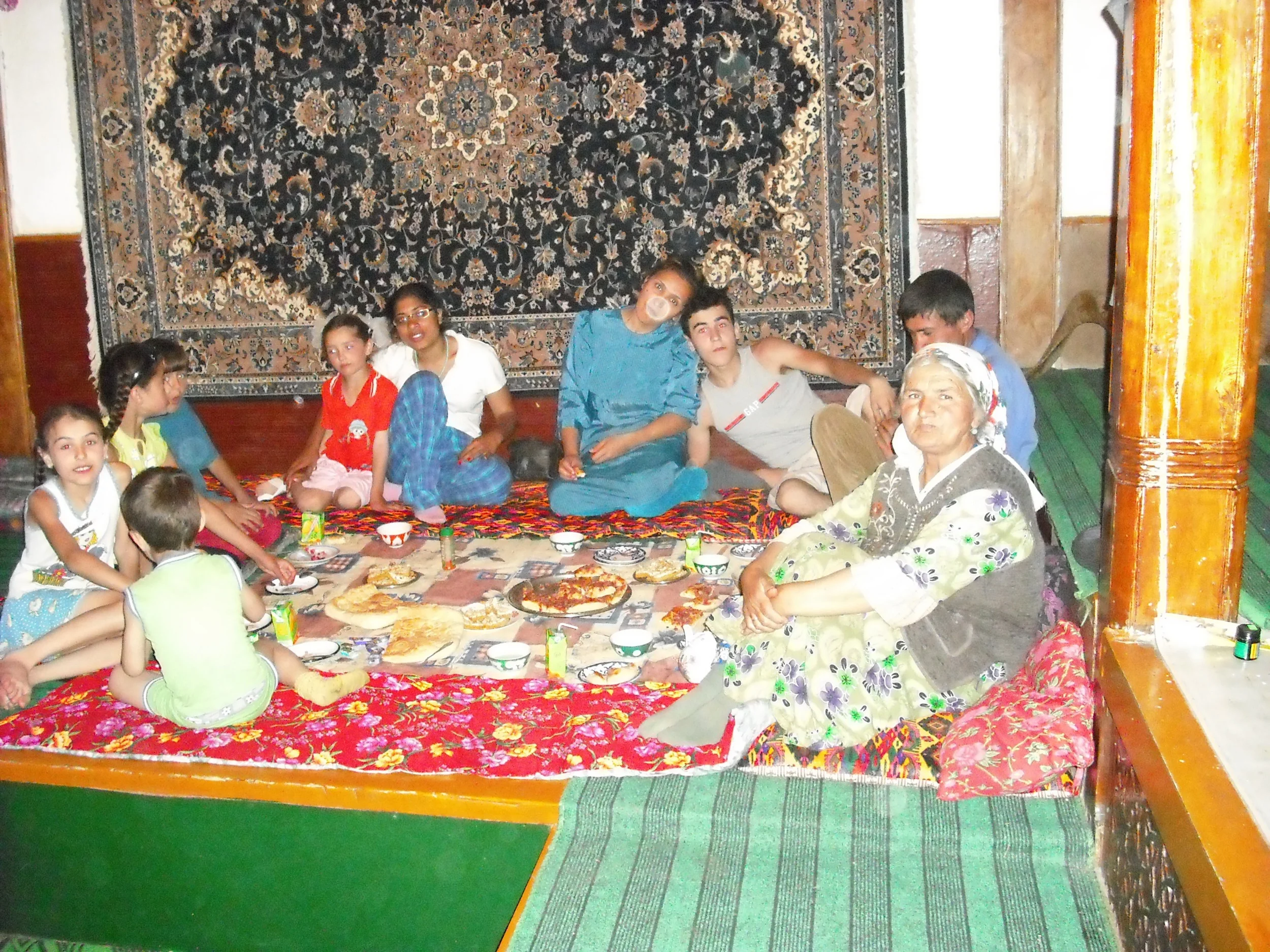 Dr. Shirinbek’s family sit around a traditional dastarkhon (tablecloth) in his home.&nbsp; It is his nephew’s birthday, so there are special treats for all!