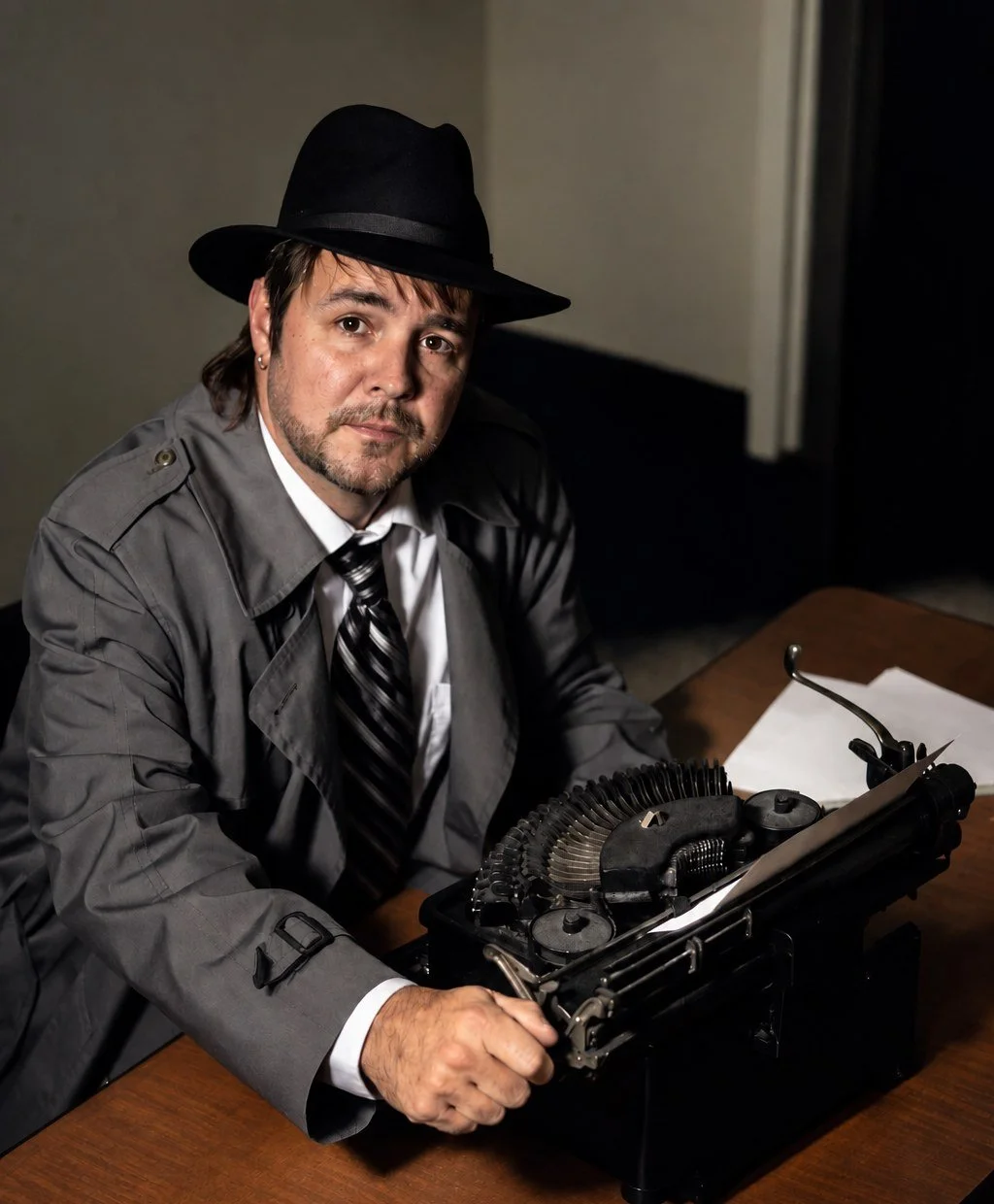 Michael Lister in a fedora and trench coat at a typewriter