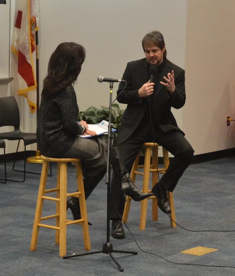 Michael Lister speaking into a microphone at an event
