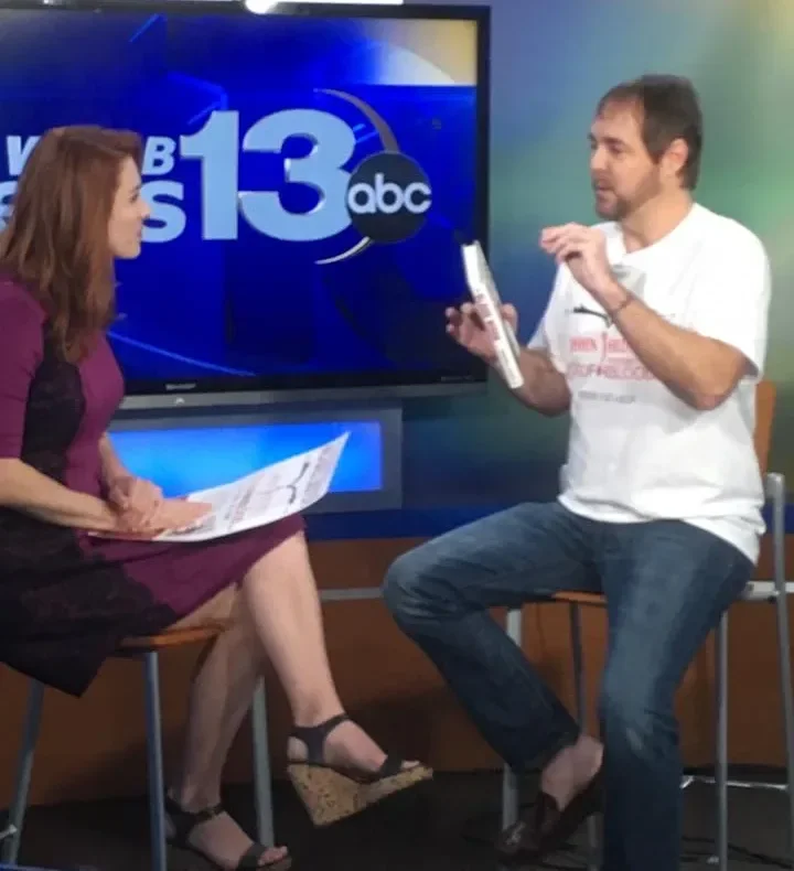 Michael Lister interviewed on WMBB ABC 13, holding one of his books