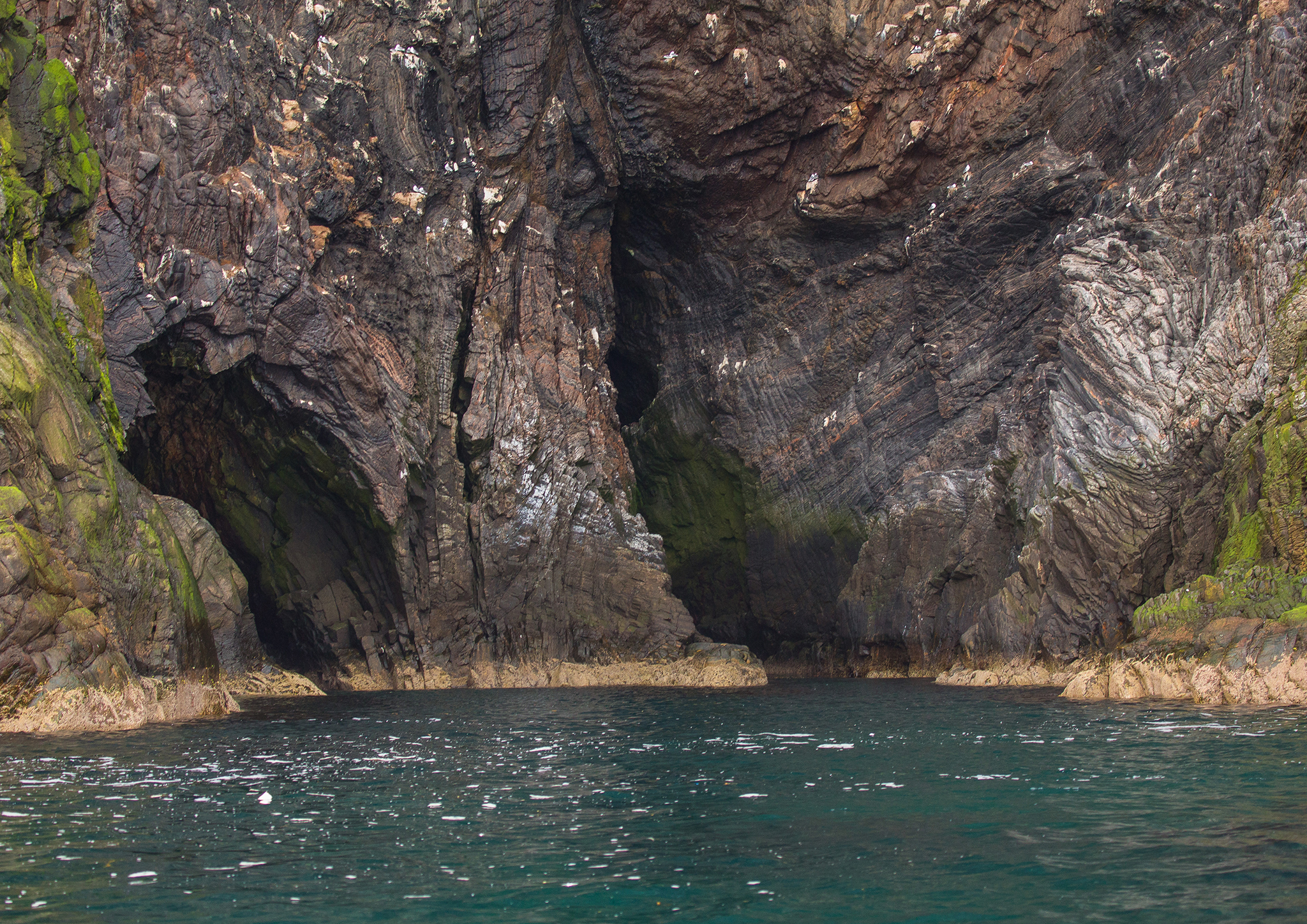    Under det 300 m høye fuglefjellet er det en 60 meters dyp grotte. Guiden i motorbåt kjører oss inn i disse hulene.   