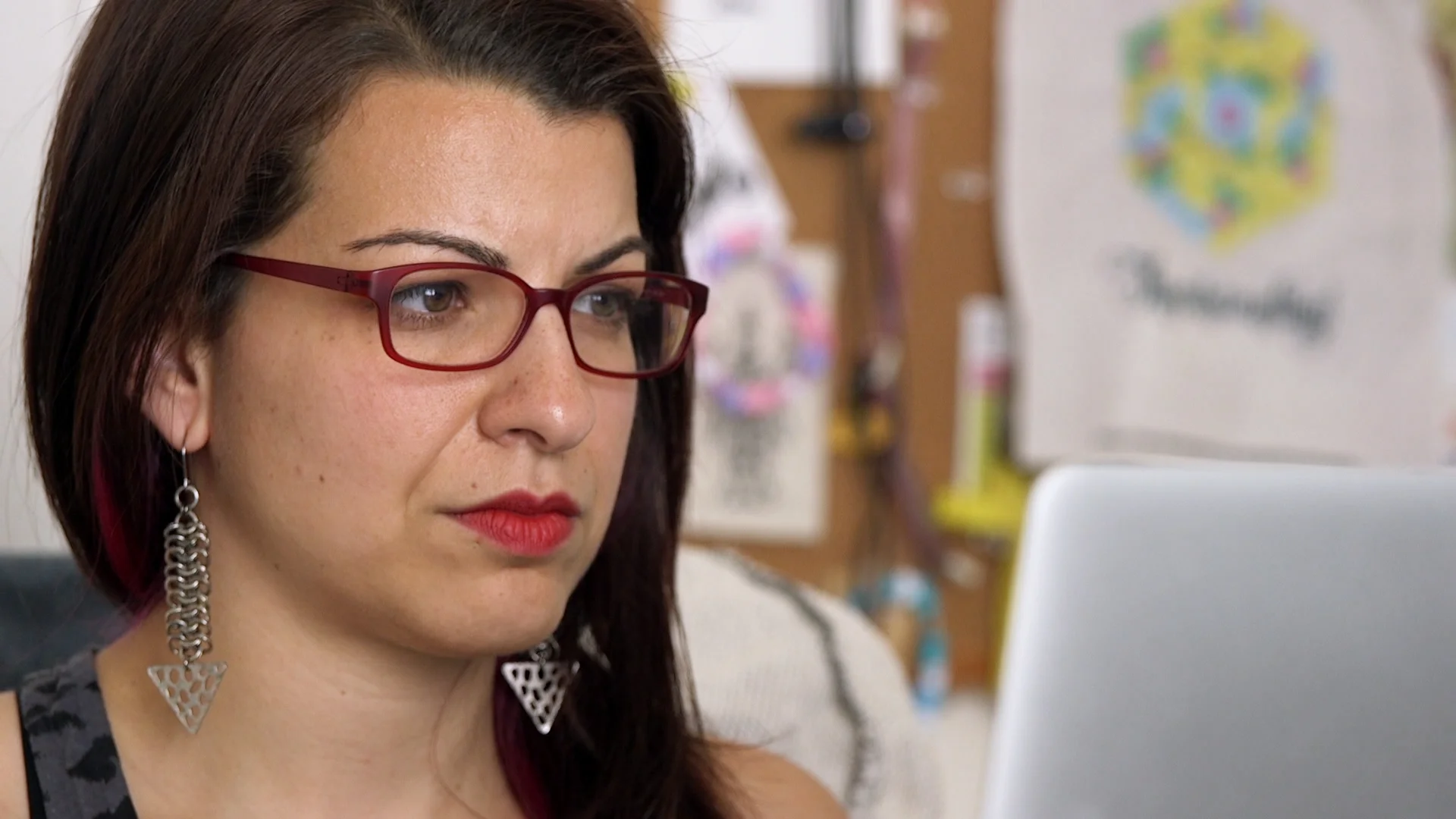Photo of Netizens subject Anita Sarkeesian looking off camera toward a laptop screen.