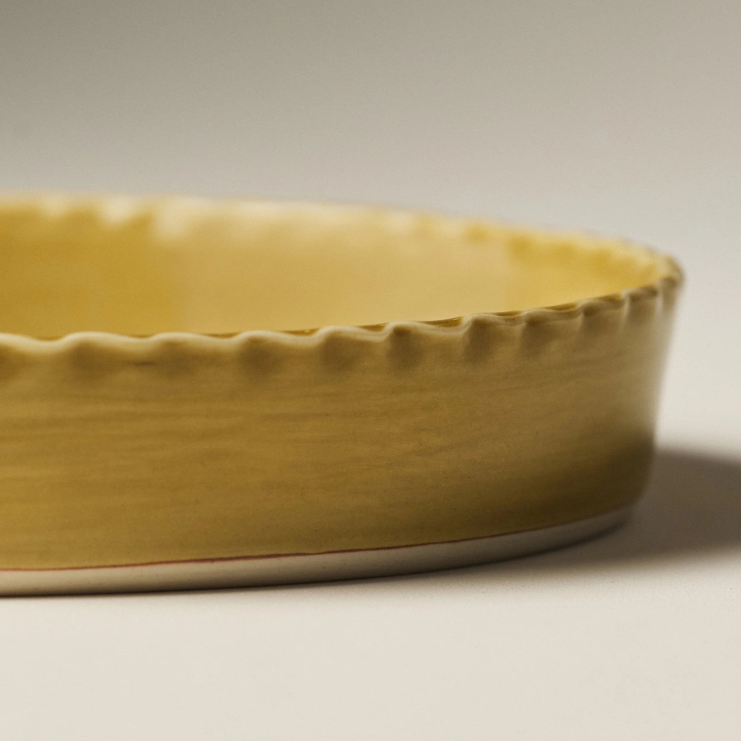 Side view of the PetitFelts Fennel ceramic platter showing its scalloped rim