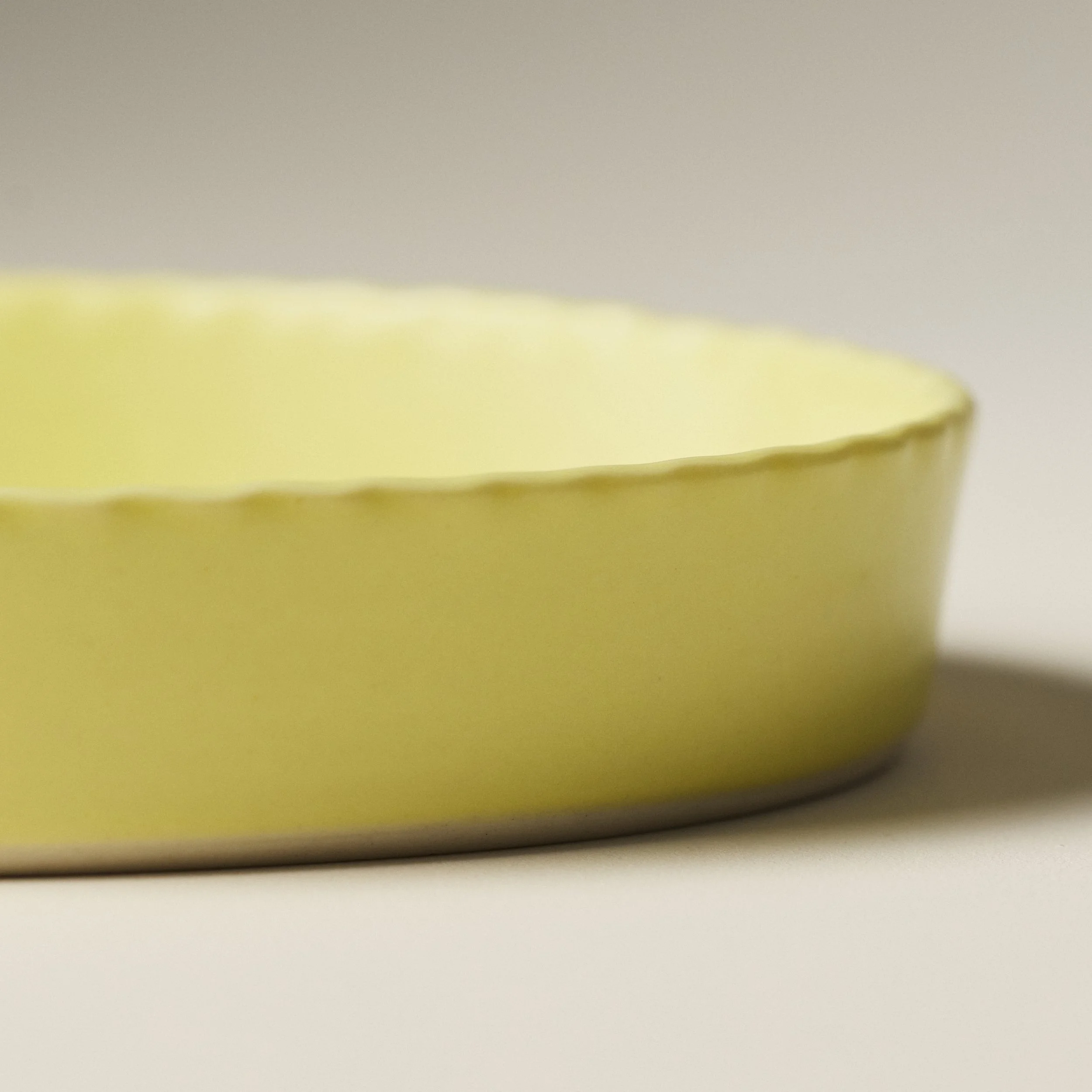 Side view of the PetitFelts Custard ceramic platter showing its scalloped rim