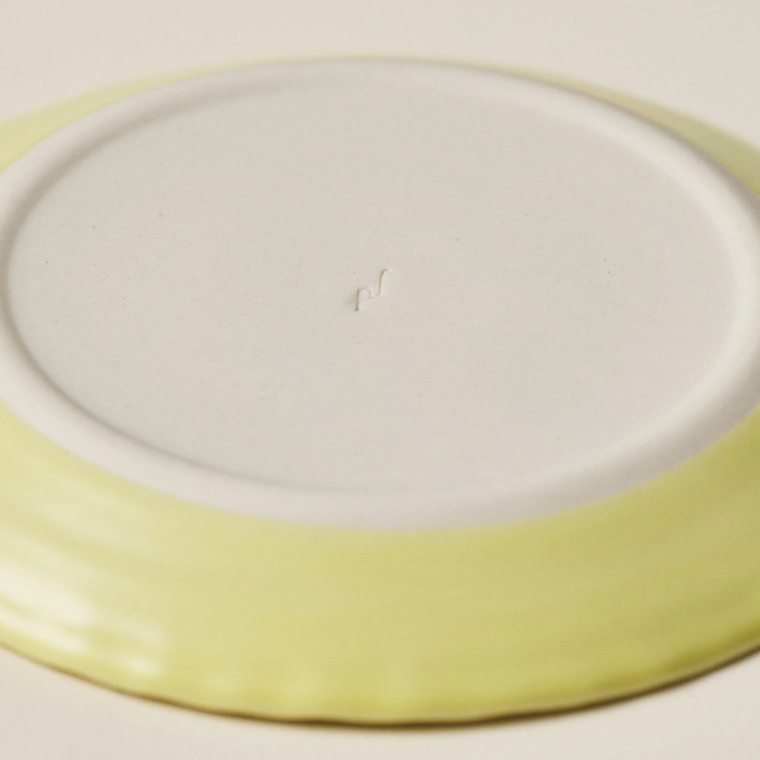 Underside detail of the PetitFelts Custard small ceramic plate showing the maker's mark