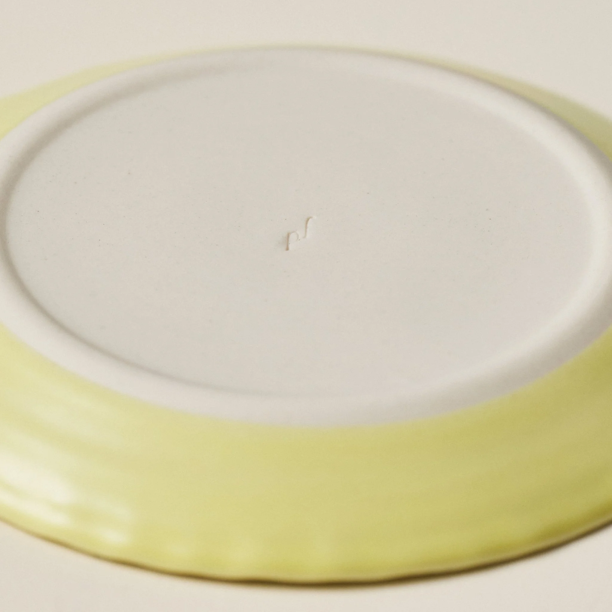 Underside detail of the PetitFelts Custard small ceramic plate showing the maker's mark