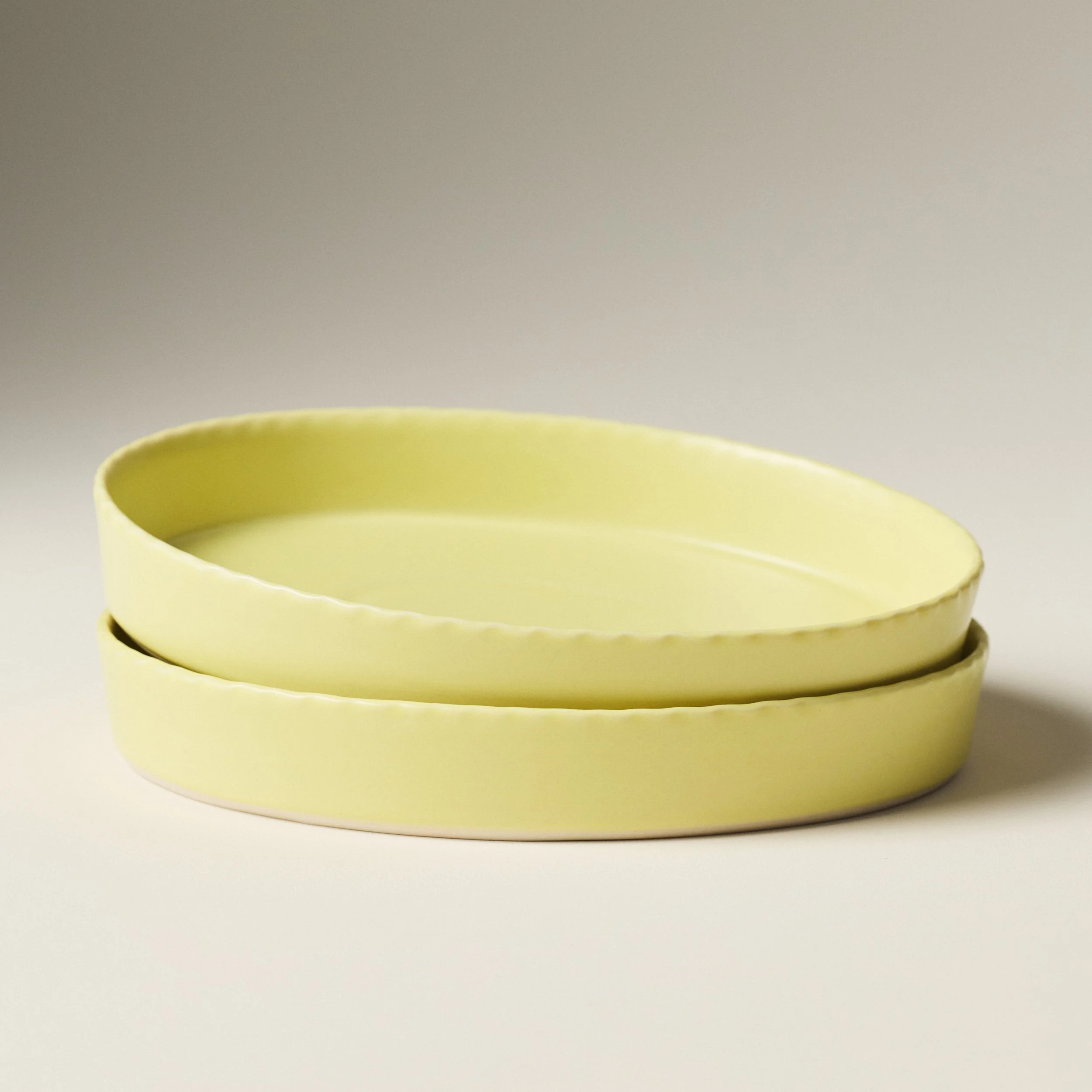 PetitFelts Custard ceramic platters stacked, showing rim detail and depth