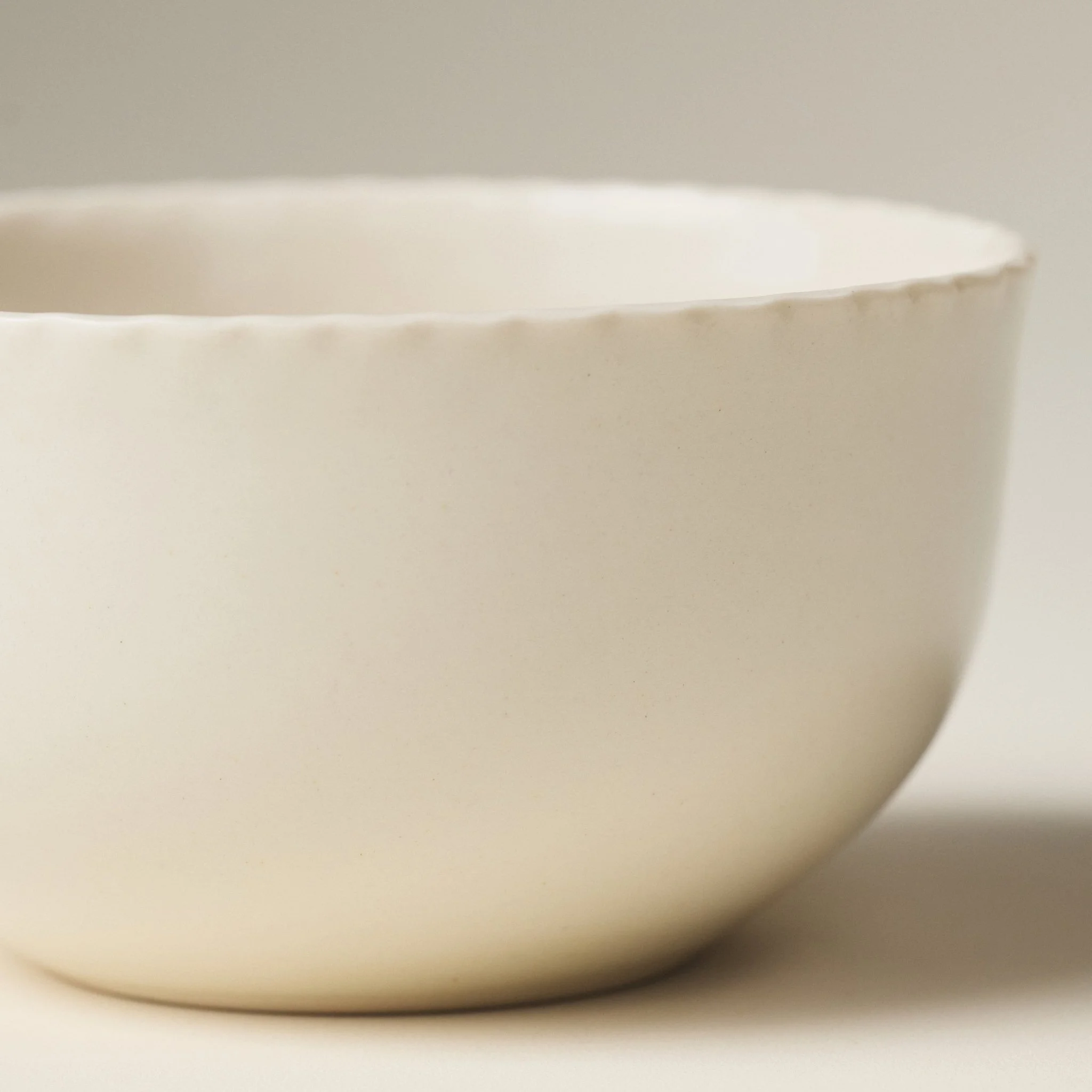 Front view of the PetitFelts Natural ceramic dinner bowl showing its fluted rim