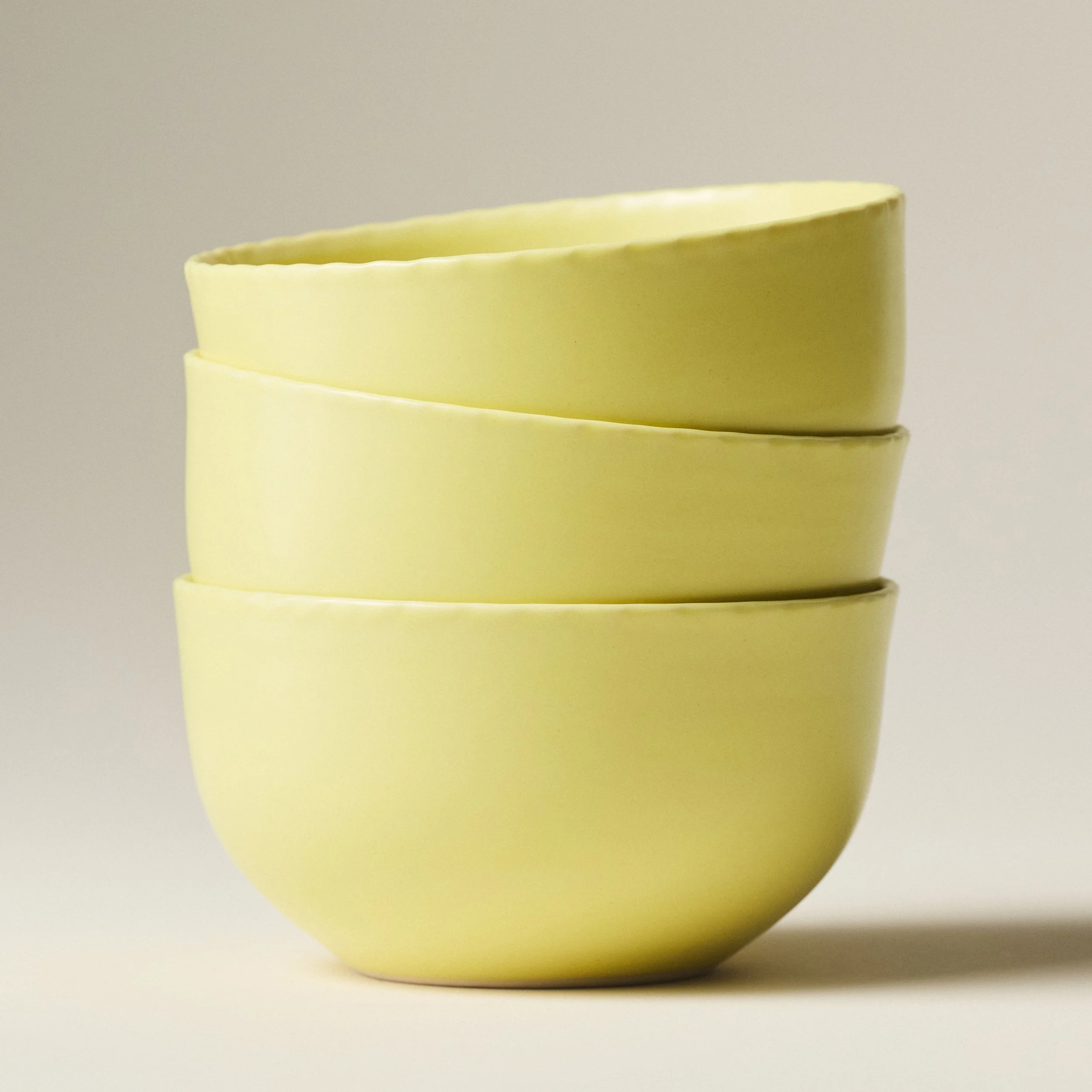 PetitFelts Custard yellow ceramic dinner bowls stacked, showing rim detail and depth