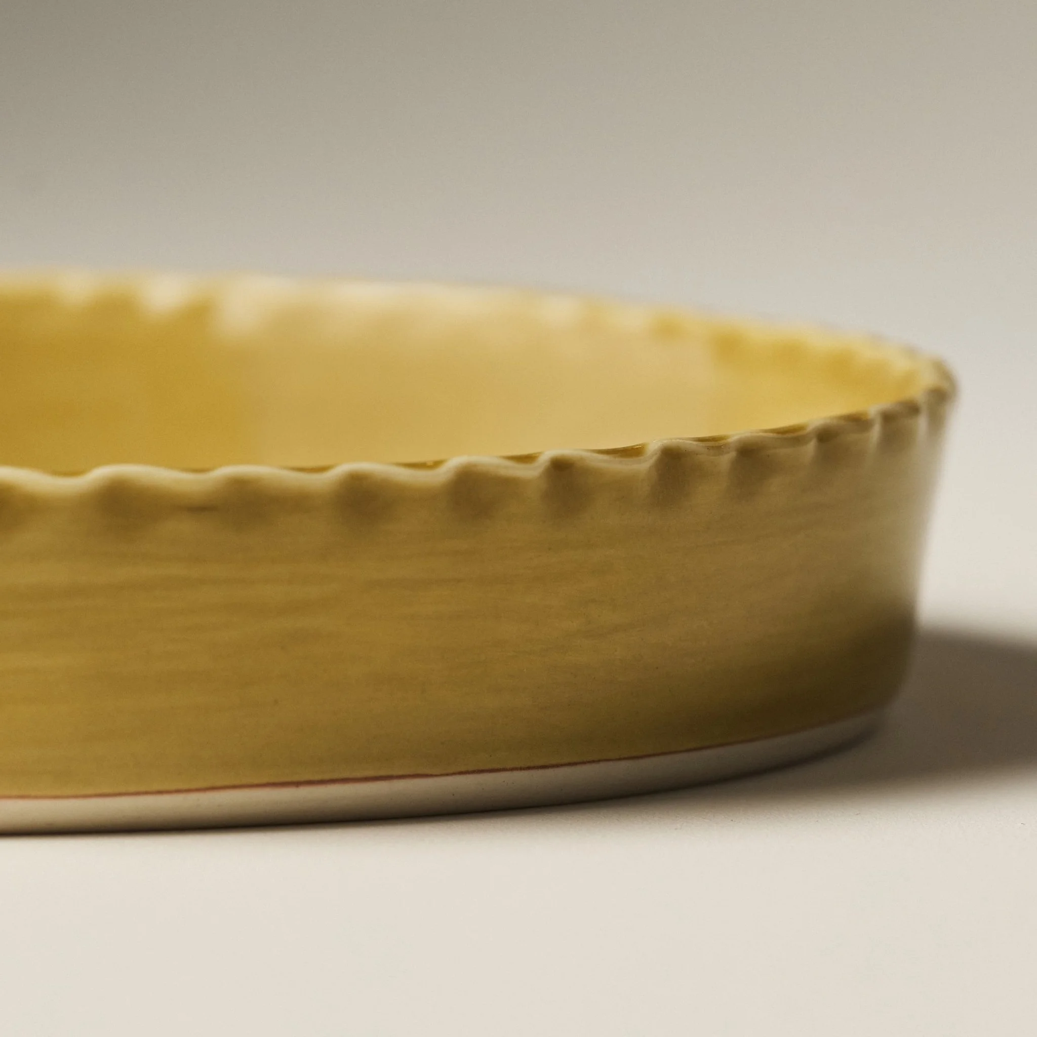 Side view of the PetitFelts Fennel ceramic platter showing its scalloped rim