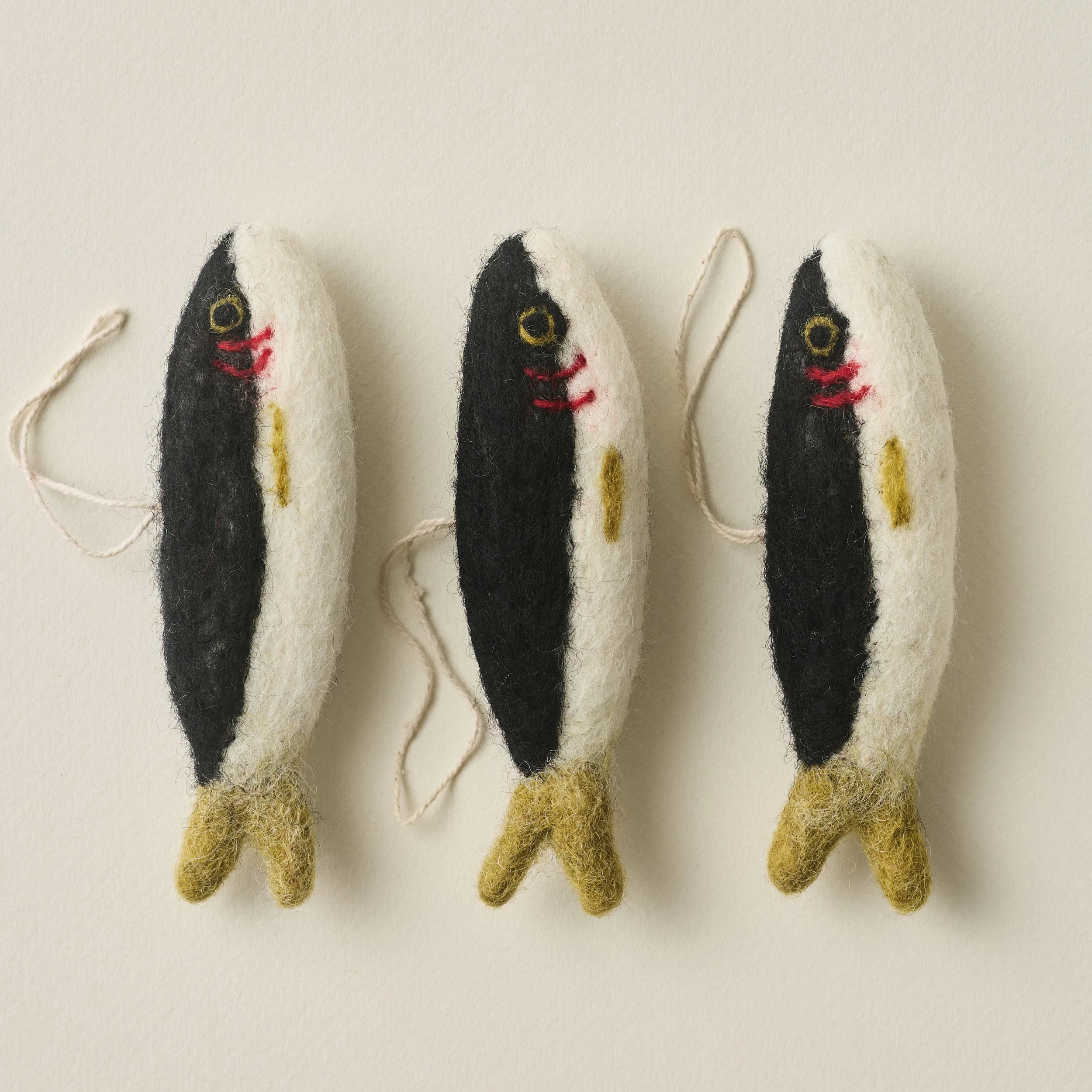 Three PetitFelts Christmas Sardine ornaments in a row