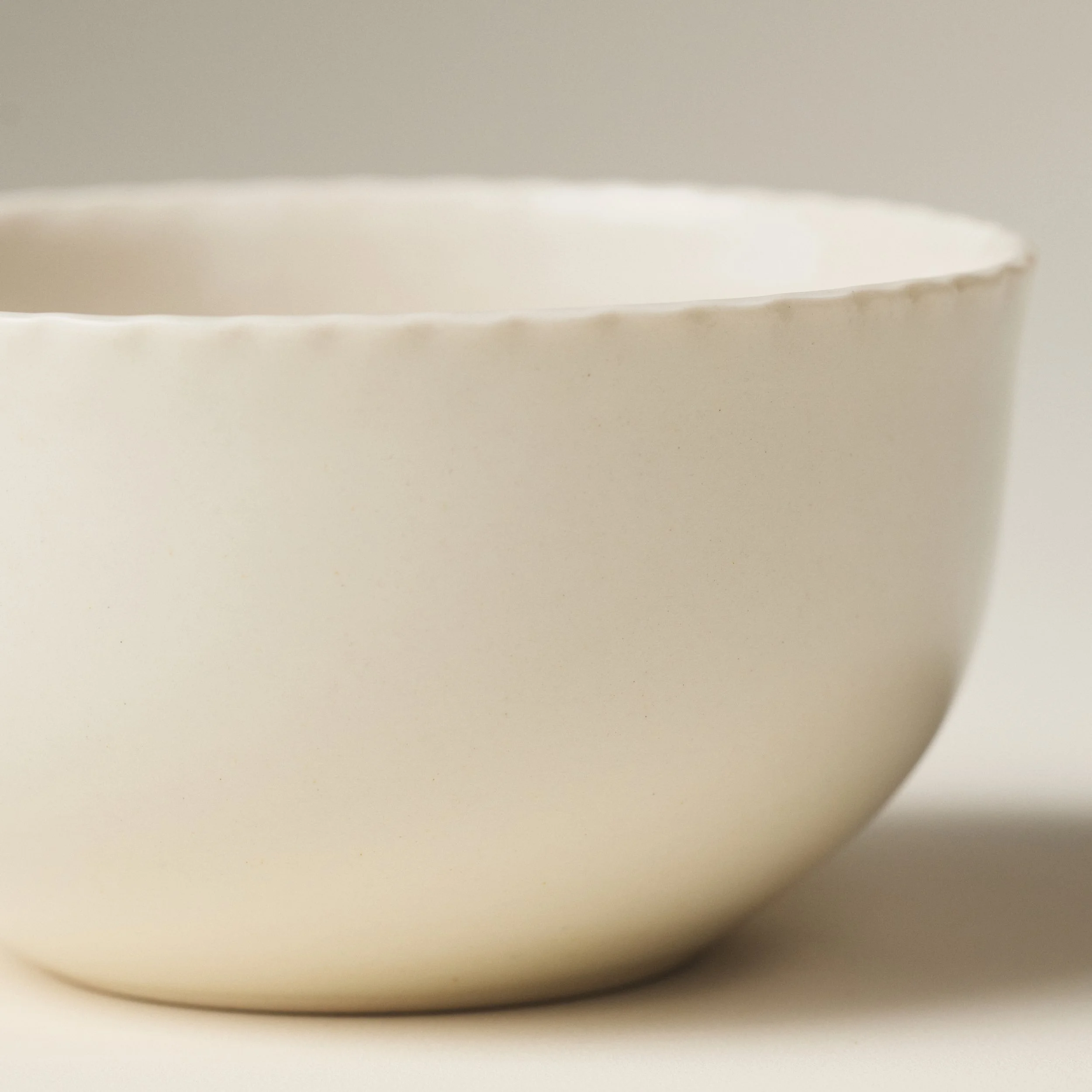 Front view of the PetitFelts Natural ceramic dinner bowl showing its fluted rim