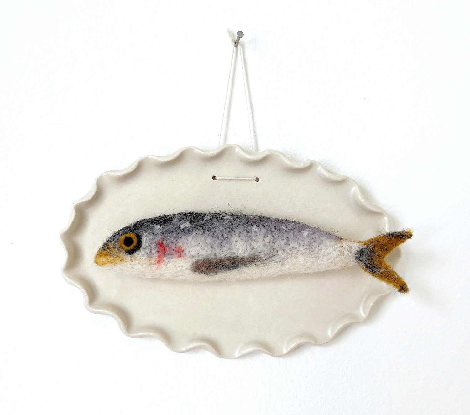 Felted fish decoration hanging on a white wall