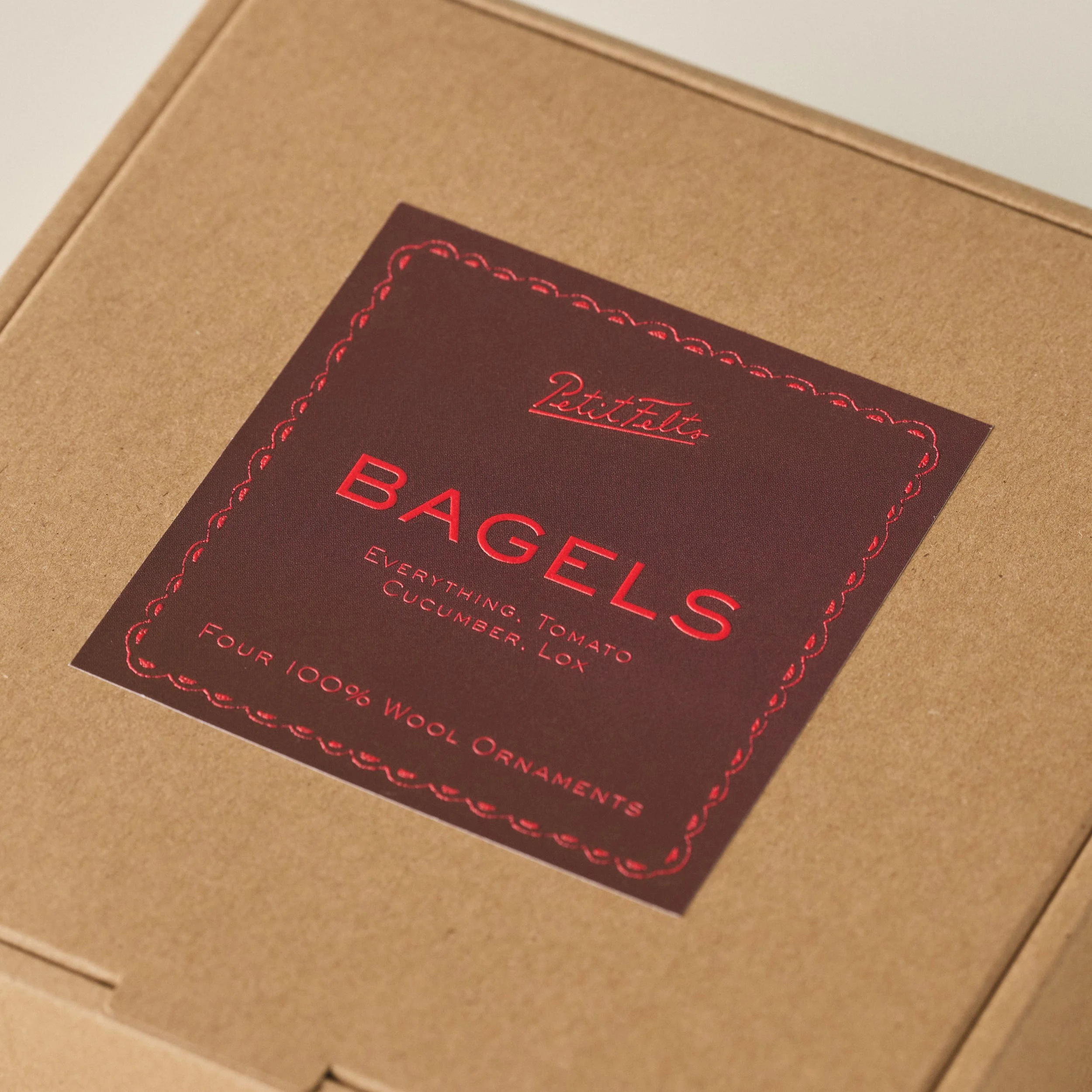 PetitFelts Bagel box detail with rich brown label and vermillion raised ink text