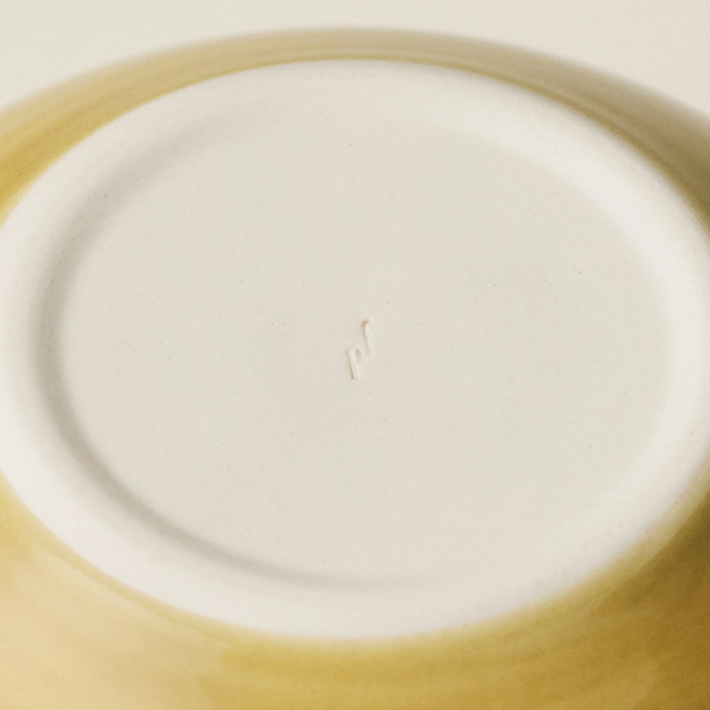 Underside detail of the PetitFelts Fennel ceramic dinner bowl showing the maker's mark
