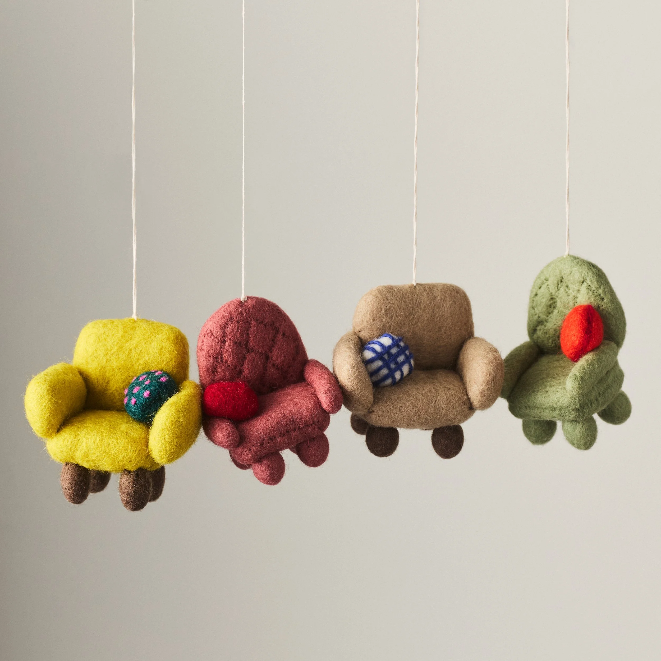 Set of four needle felted chair ornaments in a variety of colors hanging in a row.