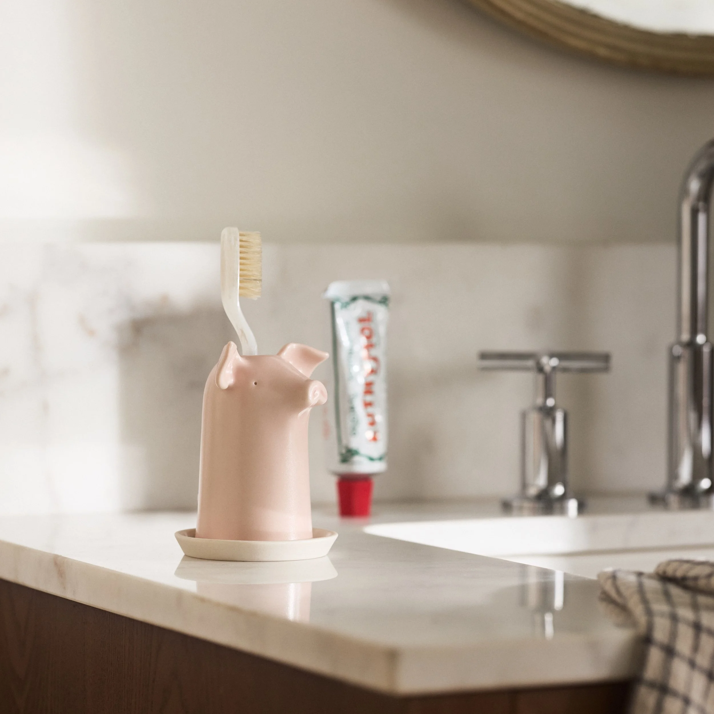 PetitFelts Rose toothbrush holder styled on a bathroom vanity with toothpaste
