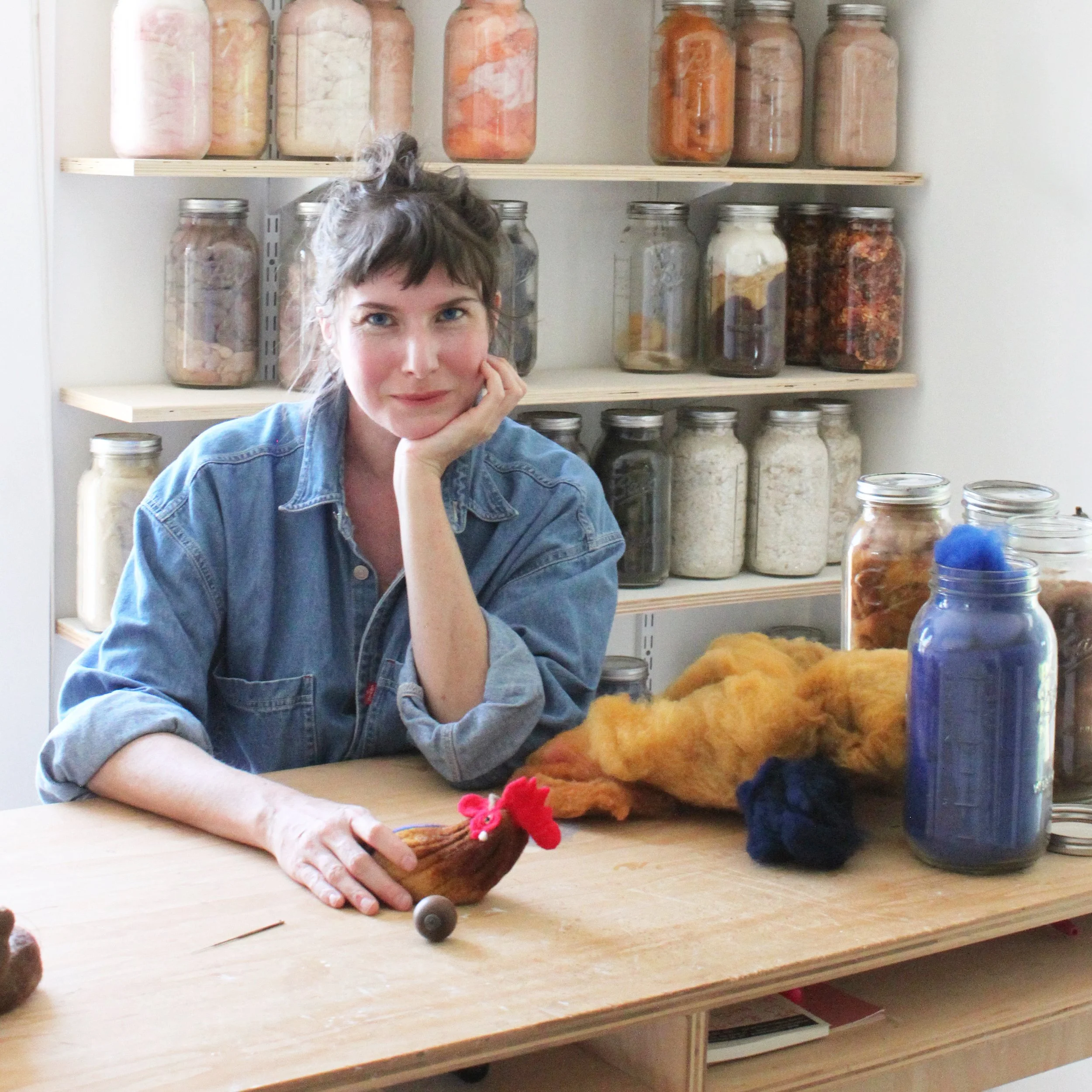 PetitFelts sitting at work bench with jars of dyed wool.