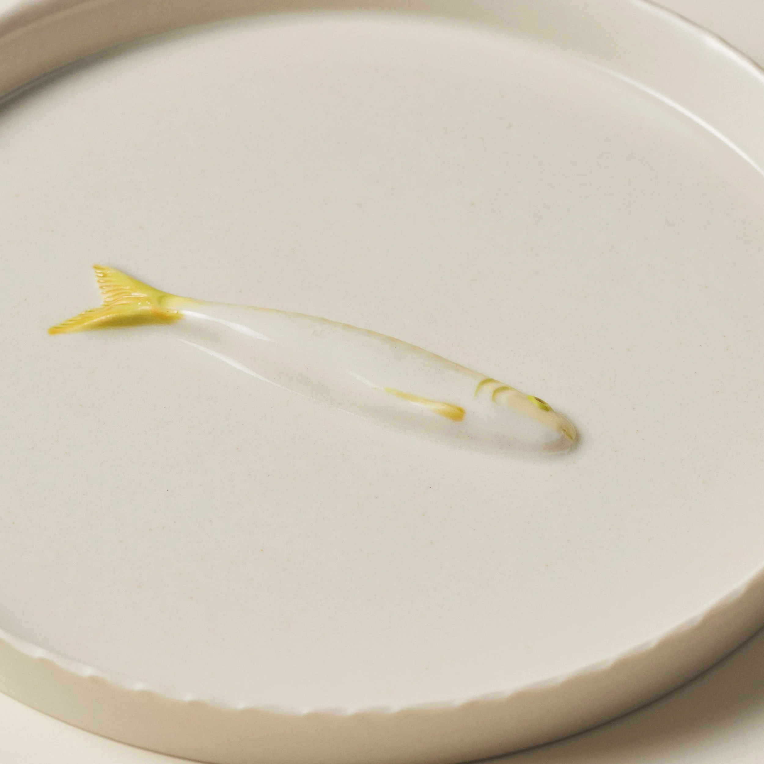 Overhead detail of the PetitFelts Big Julian Moonflower ceramic tray and sardine sculpture