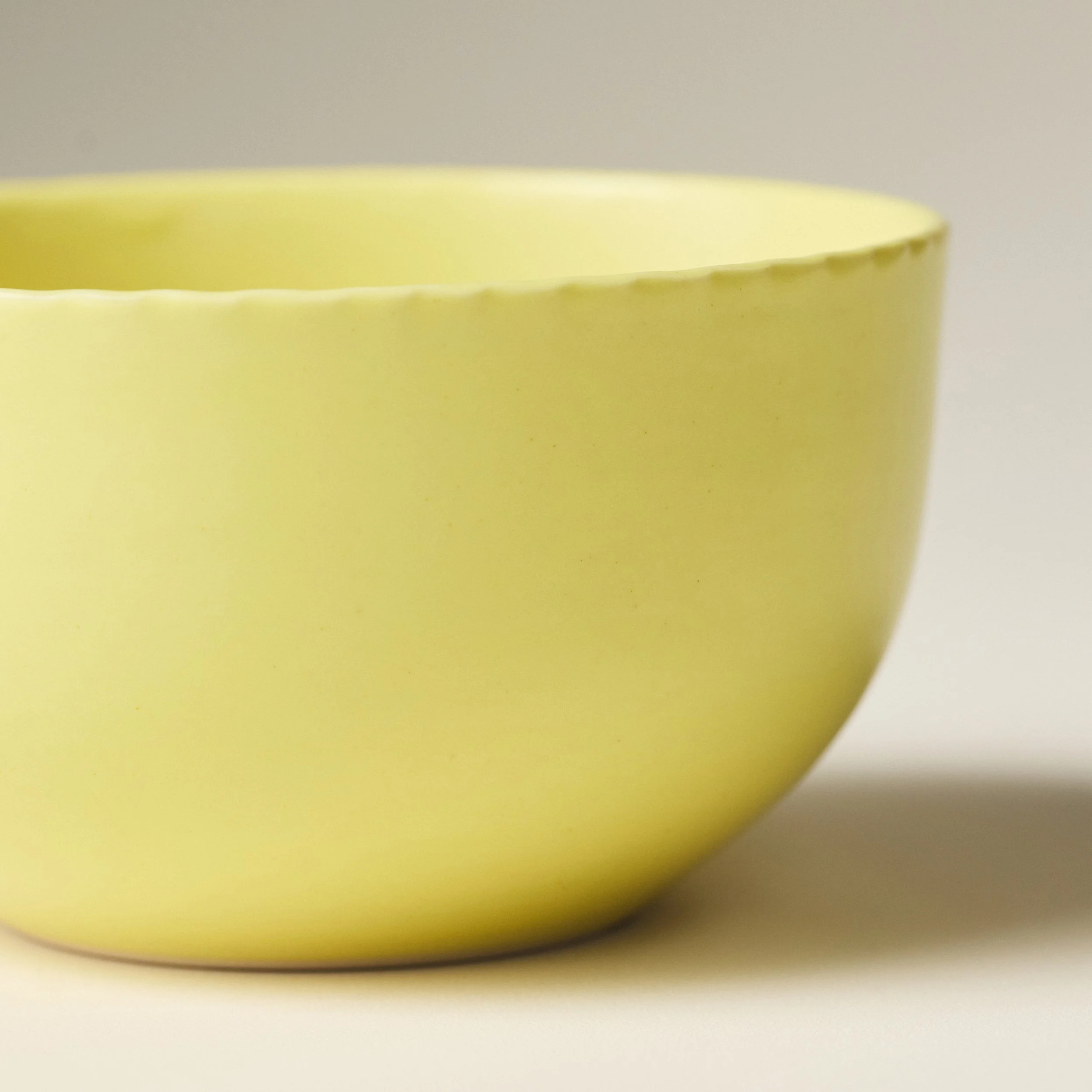Side view of the PetitFelts Custard ceramic dinner bowl showing its glazed exterior