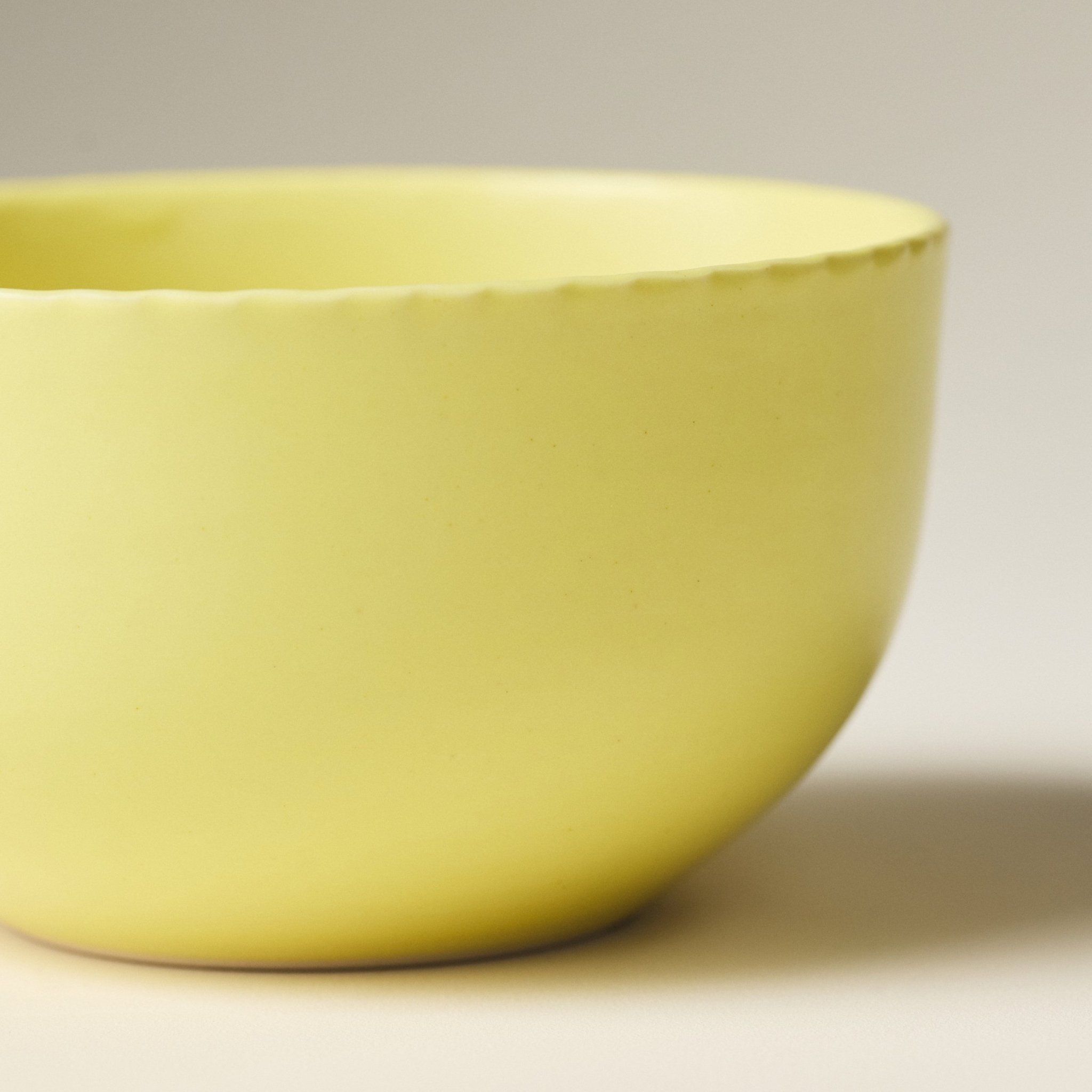 Side view of the PetitFelts Custard ceramic dinner bowl showing its glazed exterior