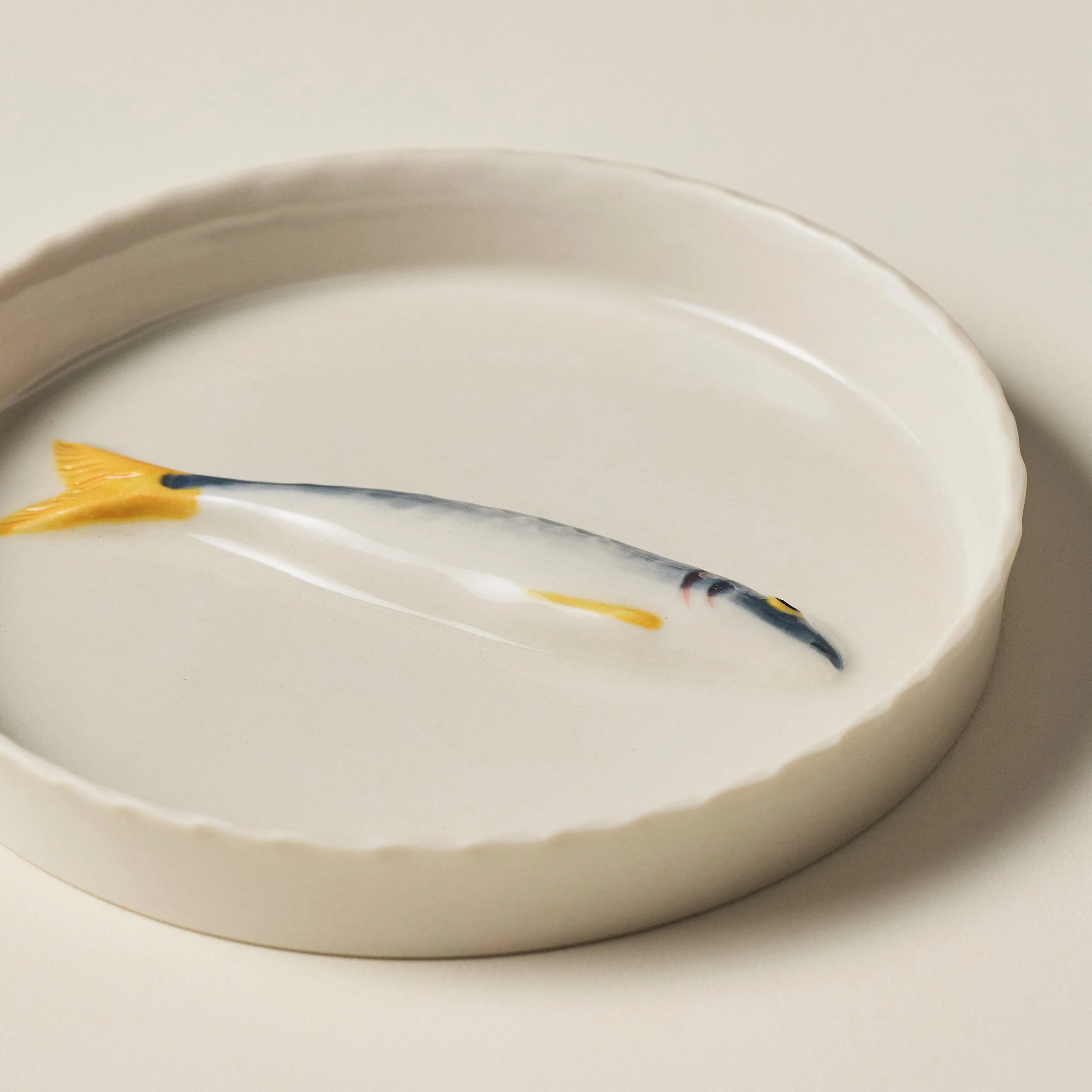 Overhead detail of the PetitFelts Little Julian ceramic catchall tray and sardine sculpture
