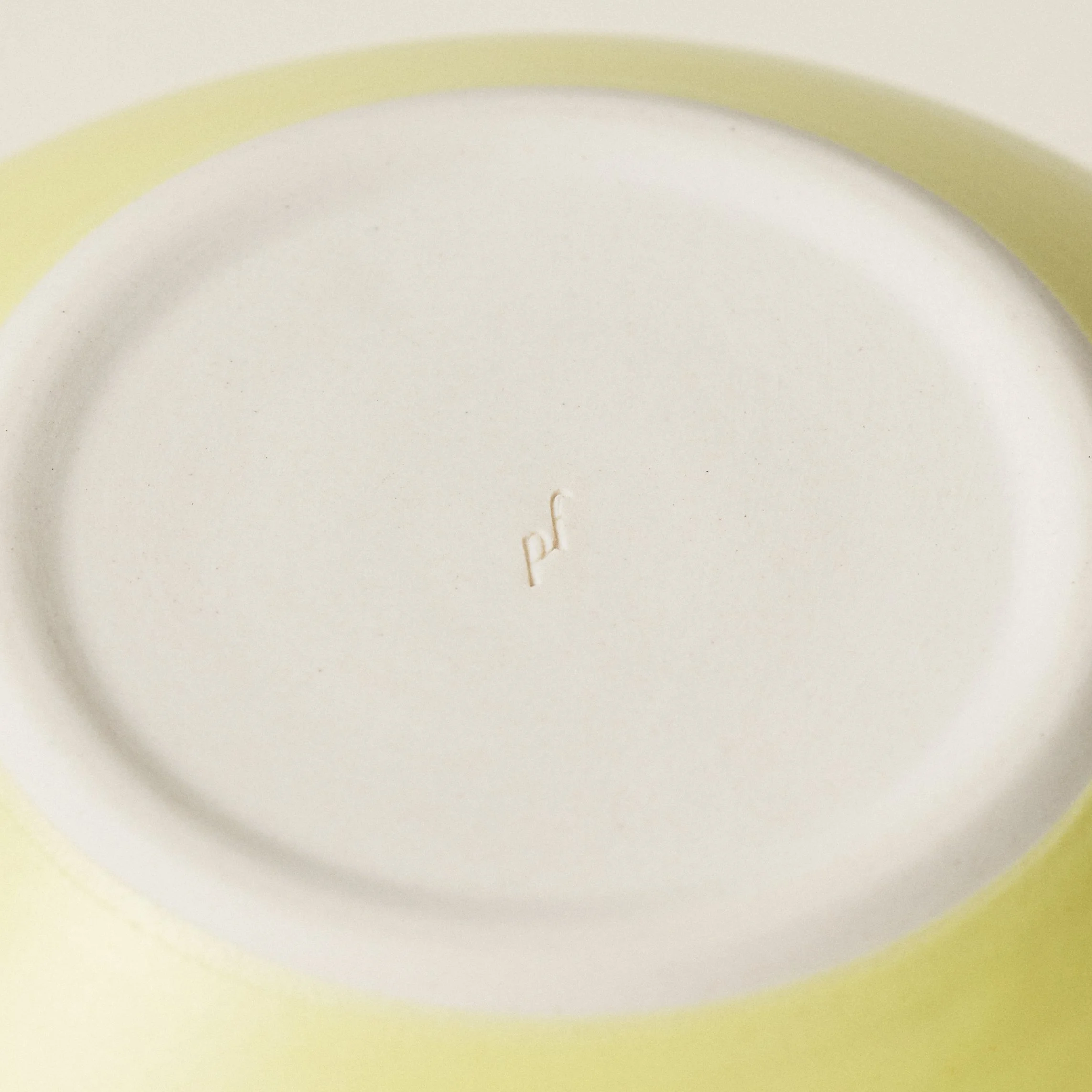 Underside detail of the PetitFelts Custard ceramic dinner bowl showing the maker's mark