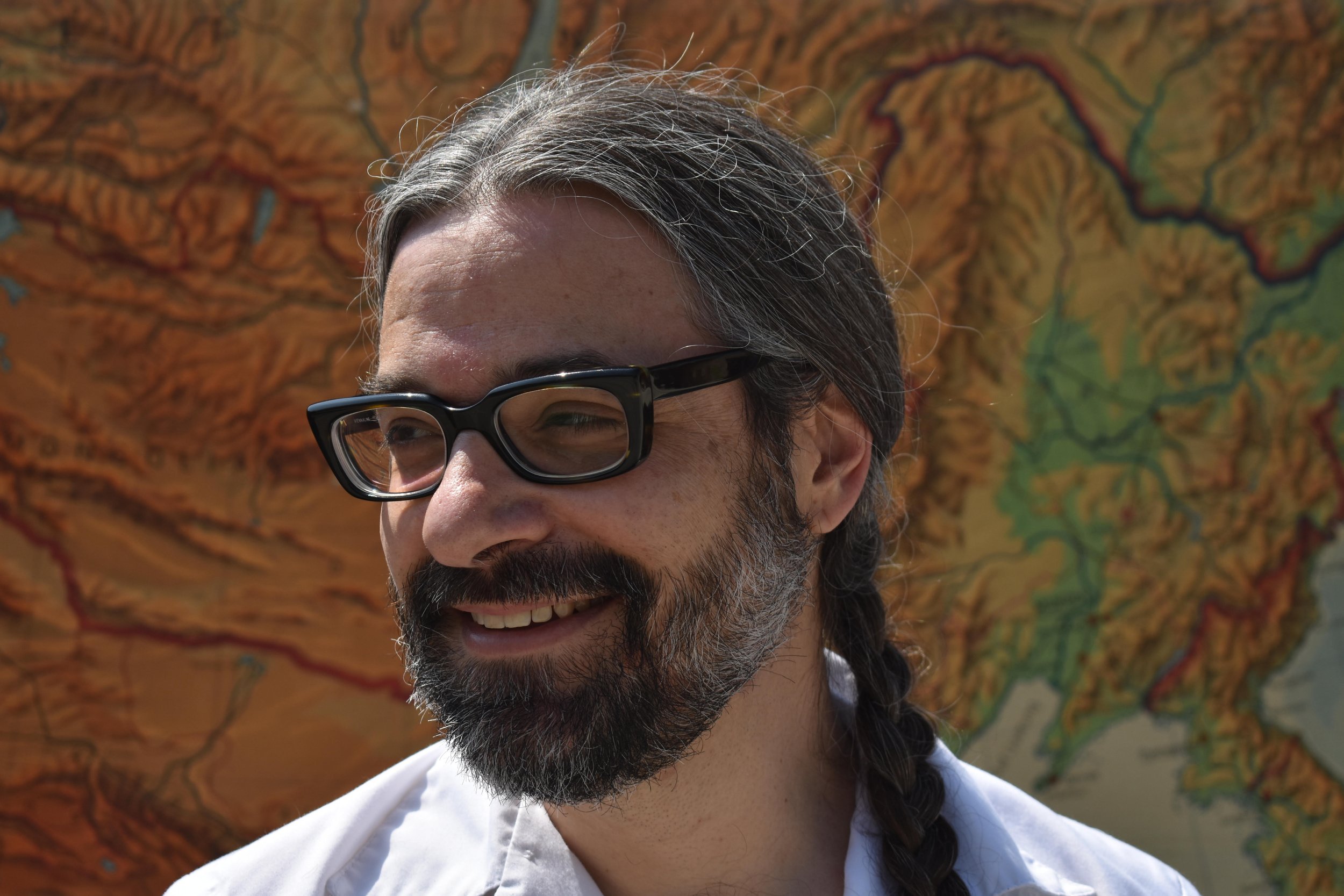 Jason Adasiewicz wearing glasses against a orange and yellow background.