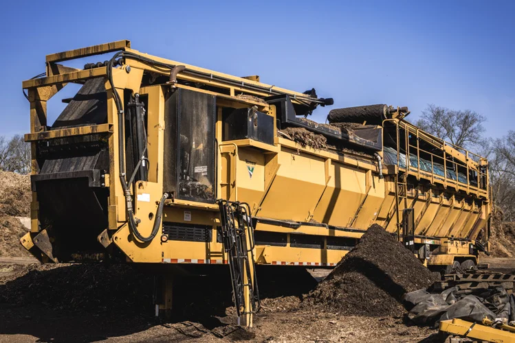 Soil screener separating rock and debris from a soil pile