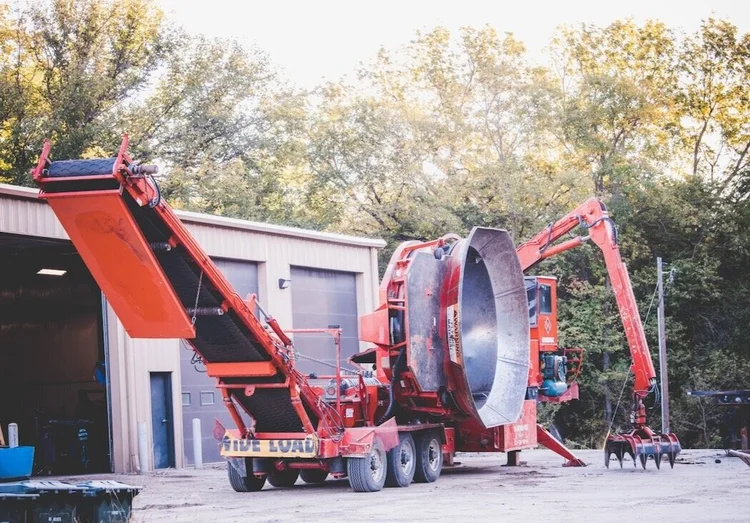 Tub grinder grinding trees on site