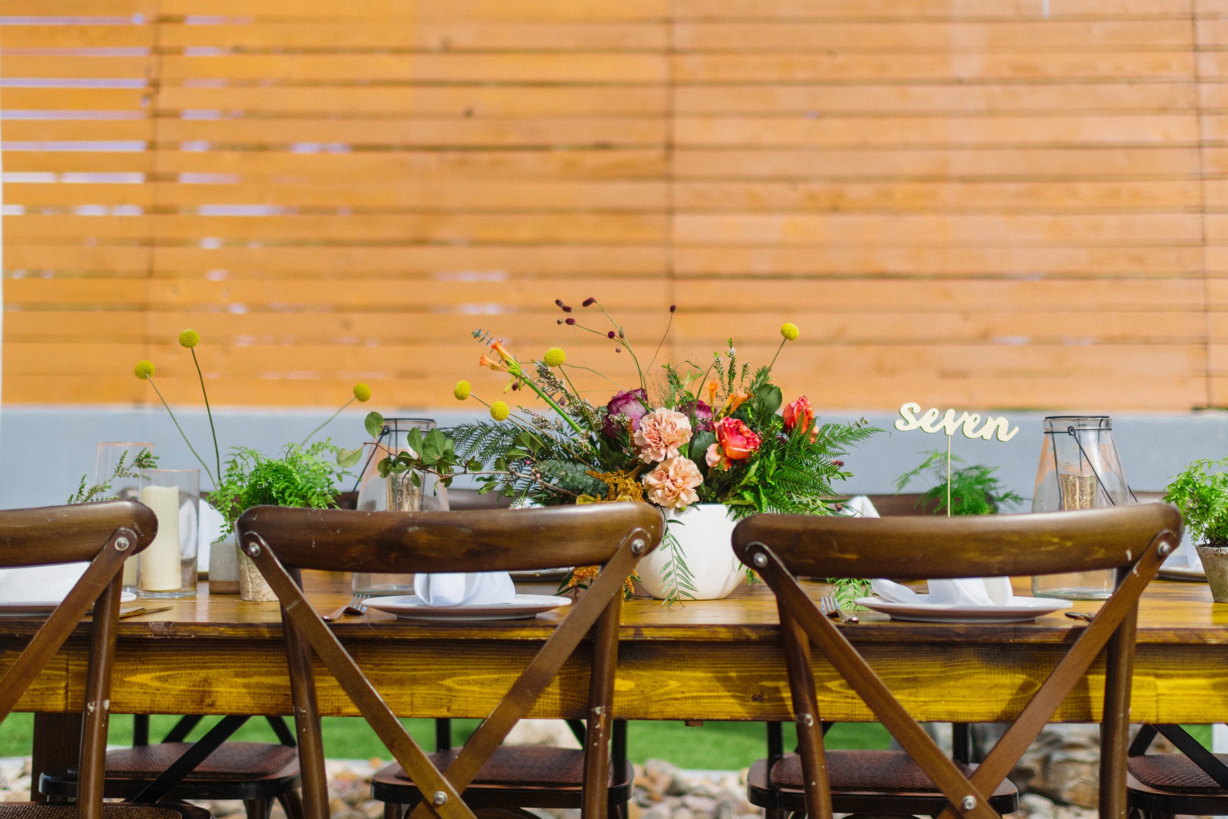 farm table wedding reception with jewel tones in purple, yellow, red and salmon with gold and potted ferns
