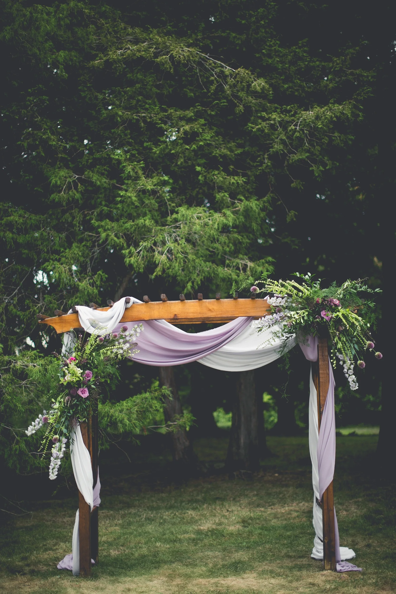 Purple wedding arch with flowers and draped fabric