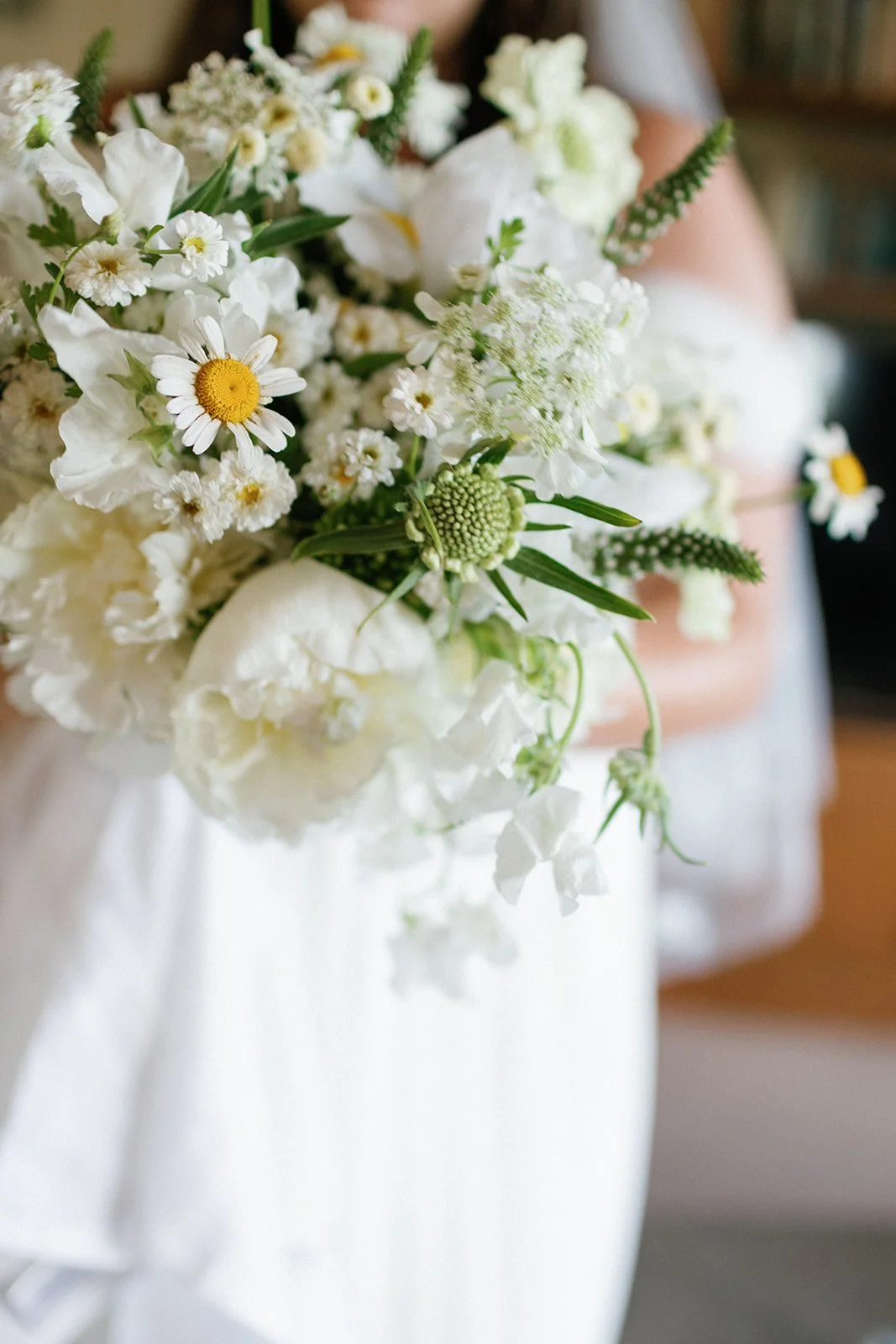 A white bridal bouquet for a june wedding with peony, oxeye daisy, chamomile, scabiosa, sweetpeas, orlaya. Wildflower themed, delicate white bouquet wedding. Sheridan, WY wedding florist Whirly Girl Flowers