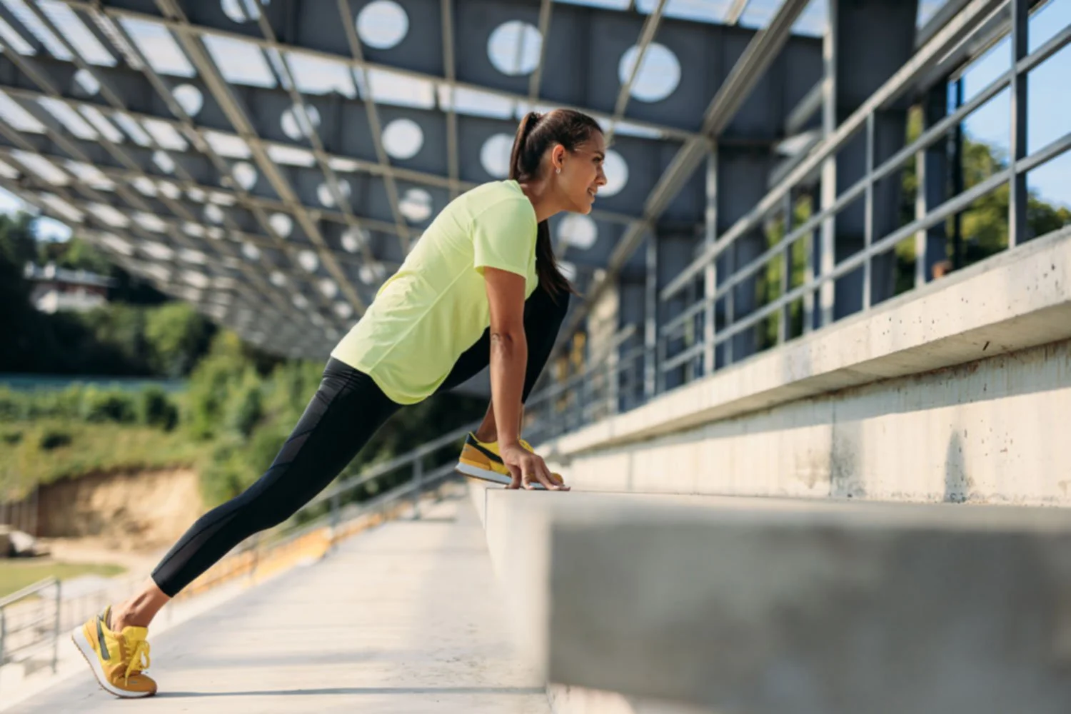 Female runner performing eccentric calf stretch on stadium steps to strengthen Achilles tendon and prevent lower leg injuries