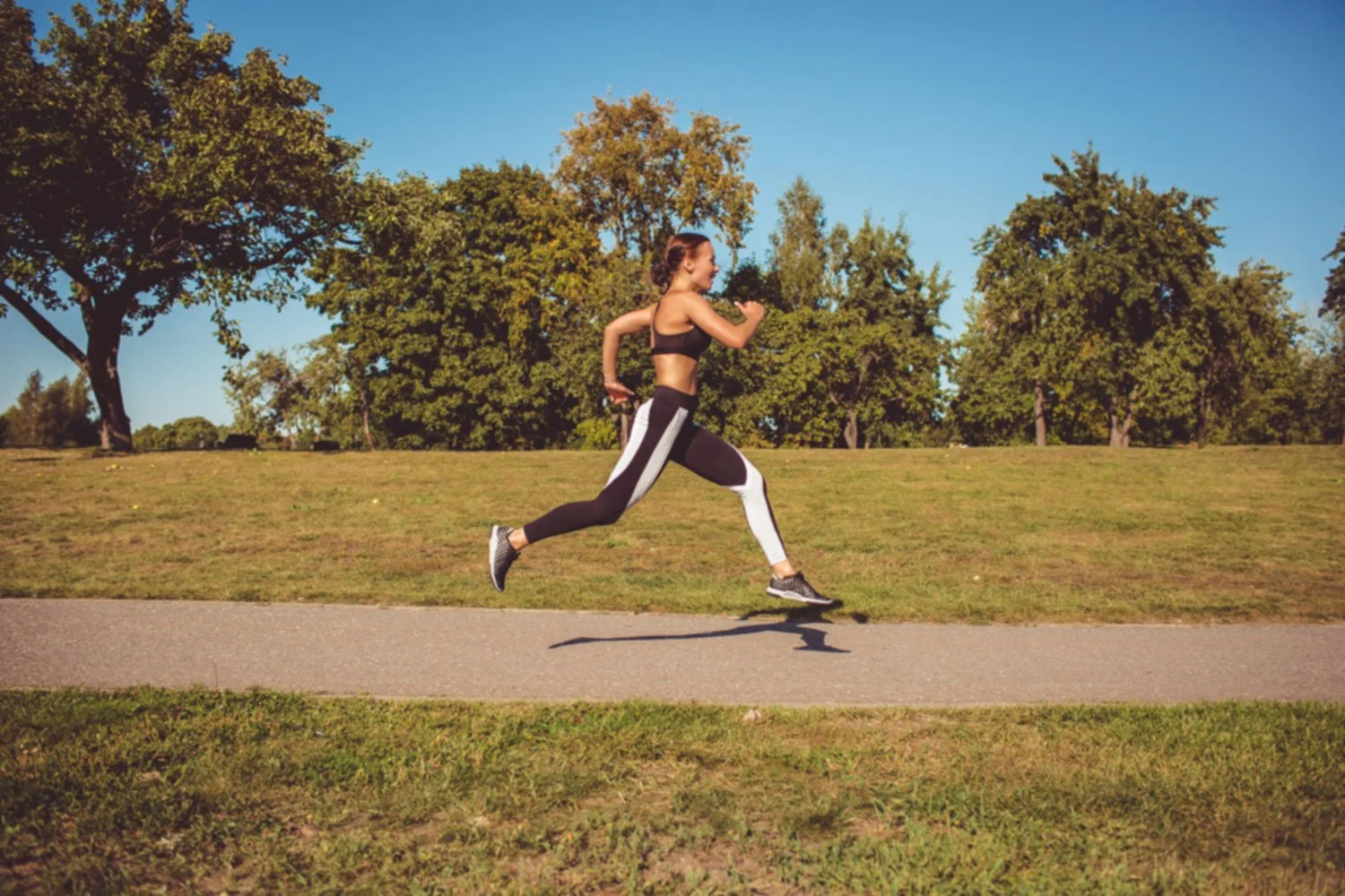 Female runner training in outdoor park demonstrating proper running mechanics and training load management for injury prevention