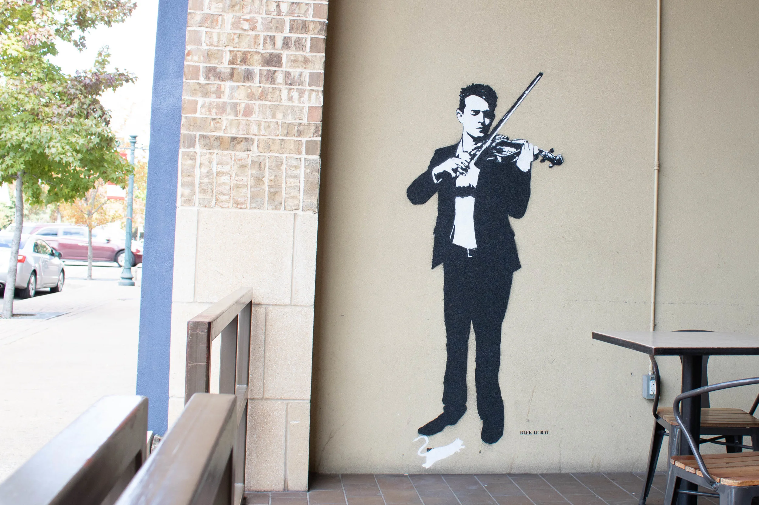 Blek le Rat’s Violinist stands tall outside of Dichotomy Coffee & Spirits at 508 Austin Avenue.