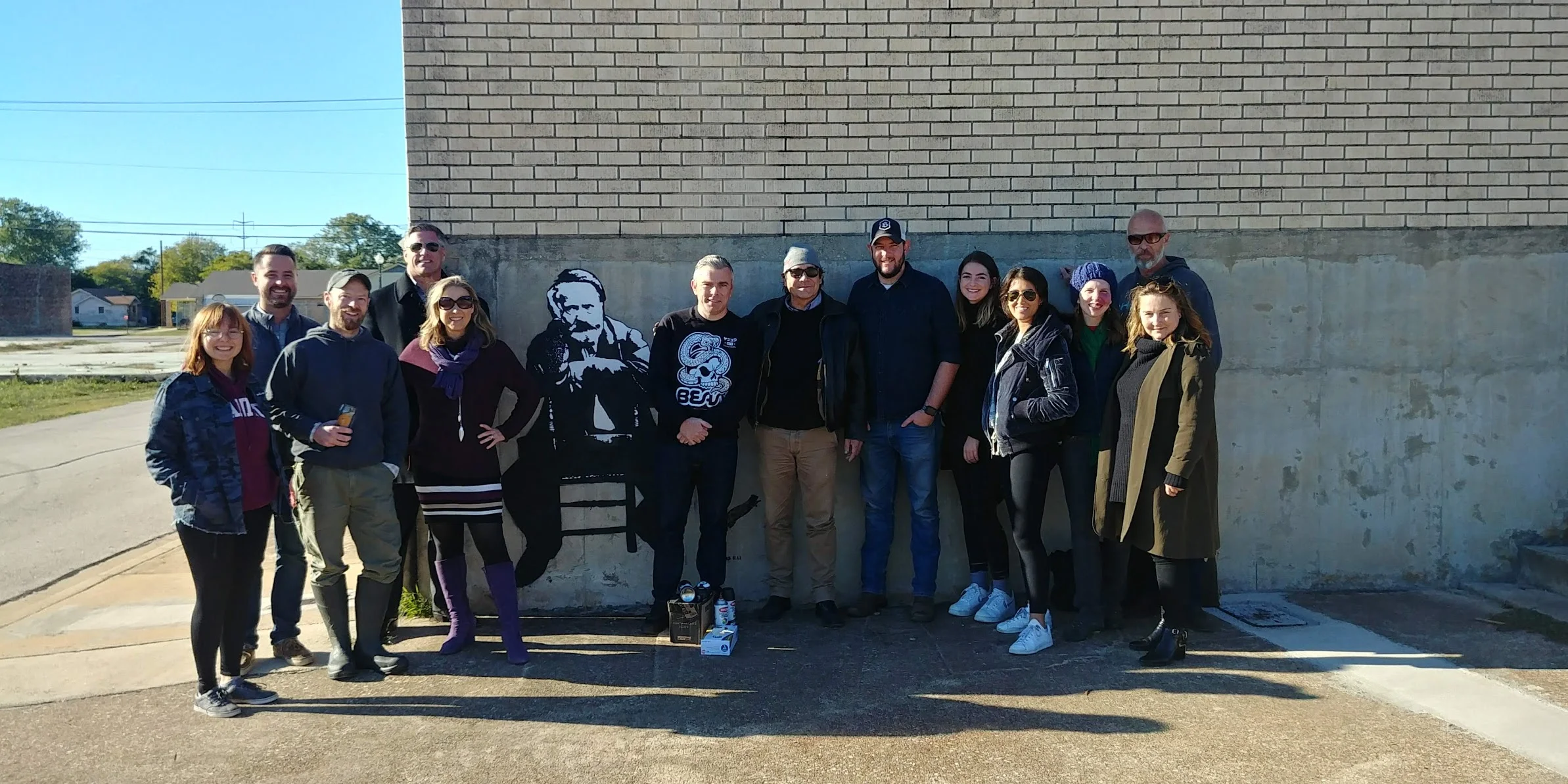 Blek le Rat and supporters stand next to one of his street art piece’s in Waco, Texas