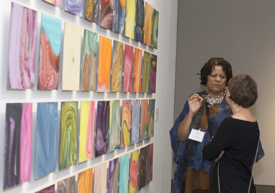 Visitors discuss Fran O'Neill's forty untitled panels at the Confronting the Canvas members' preview. Image courtesy of Thomas Hager.