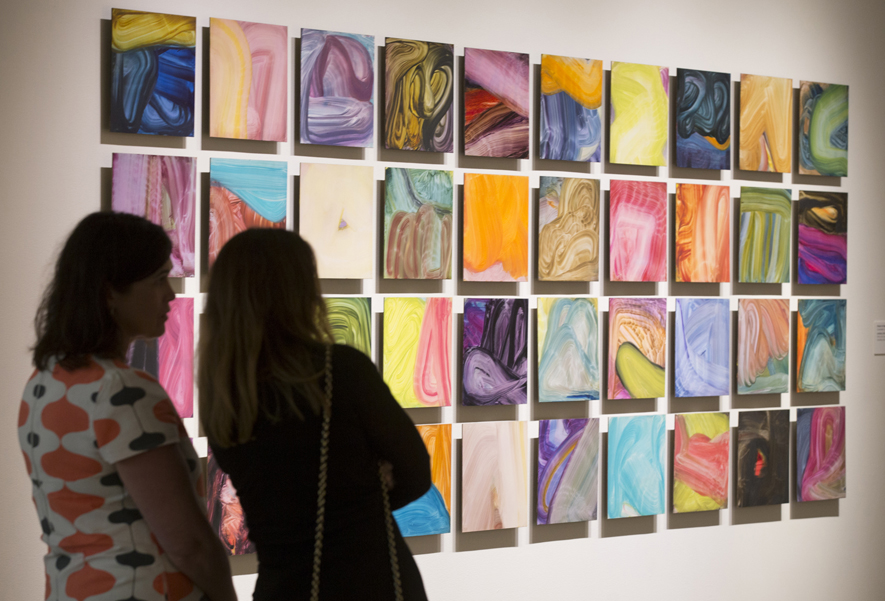 Fran O'Neill discusses her process in front of the grid of forty untitled panels at the Confronting the Canvas members' preview. Image courtesy of Thomas Hager.