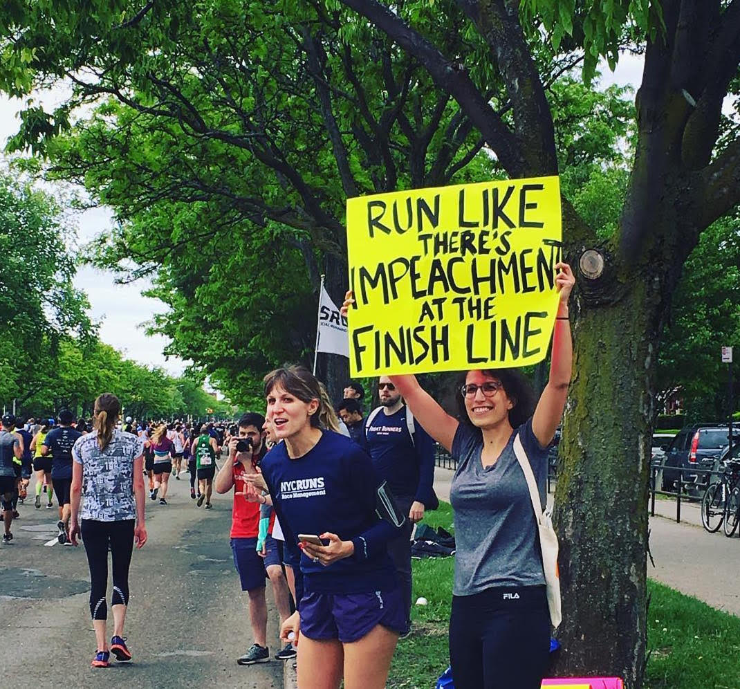 Kara (holding the sign) near the end of this year's Brooklyn Half Marathon. The promise of impeachment might actually motivate us to run next year!