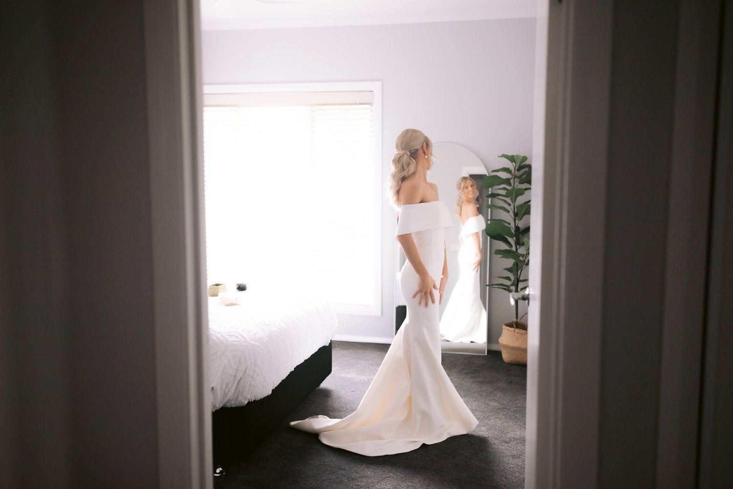 Bride in white dress looking in mirror