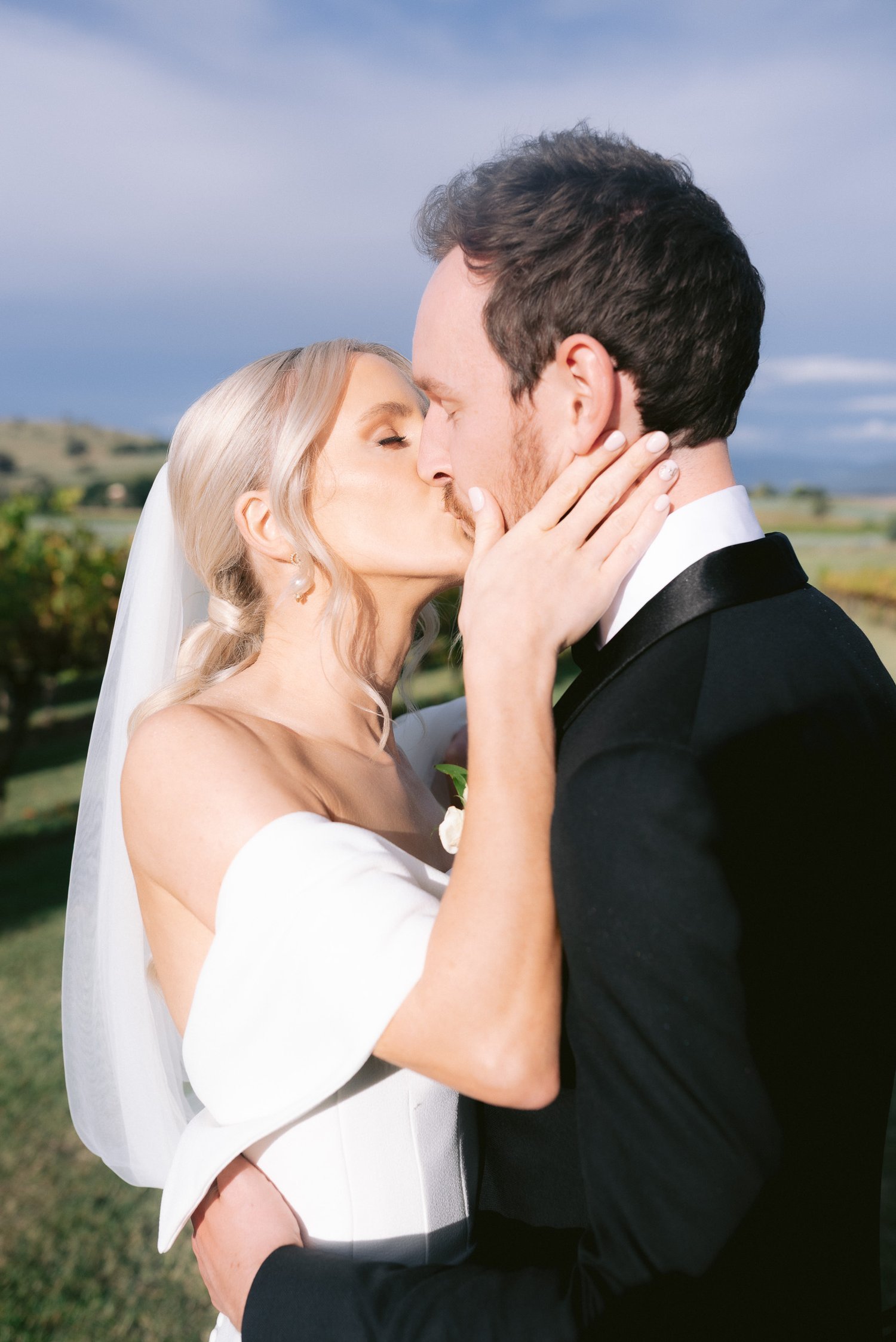 Bride and groom kissing outdoors on their wedding day.