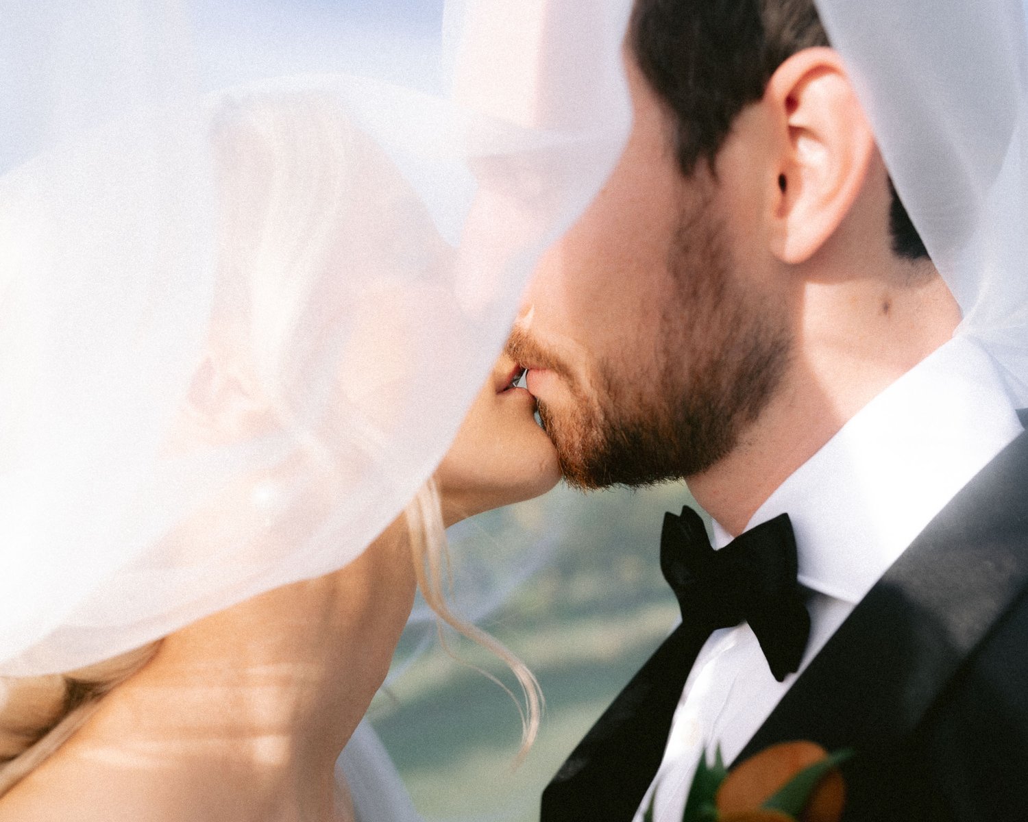 Bride and groom kissing under veil