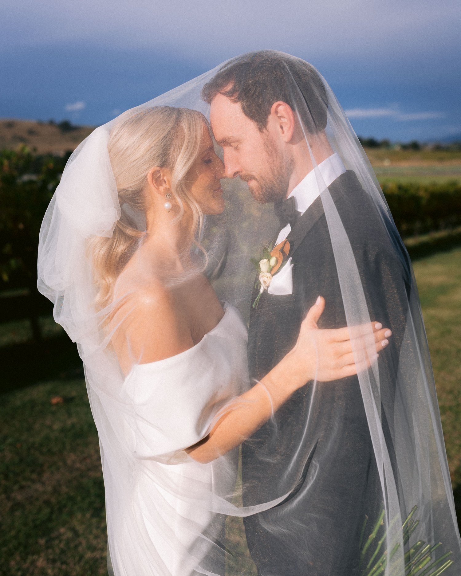 Bride and groom embracing under a veil outdoors on a sunny day in the Yarra Valley.